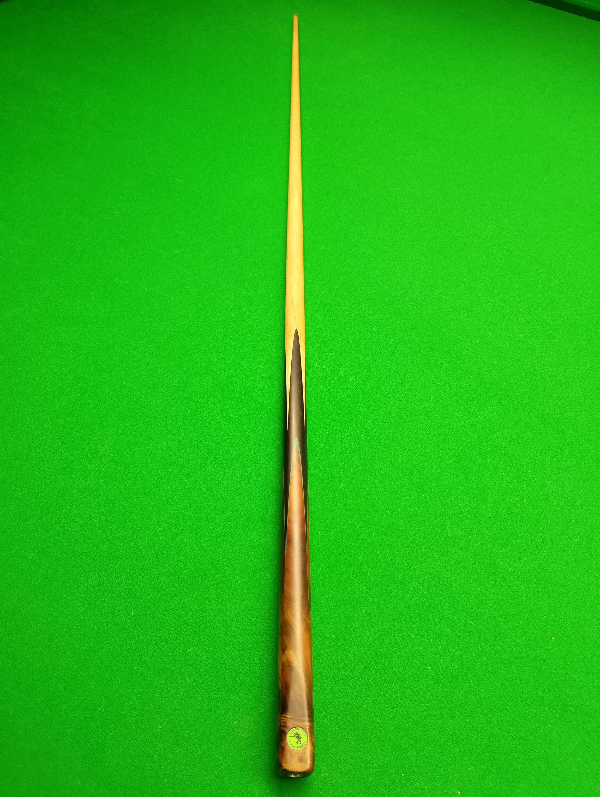 A billiard cue stick on a green pool table.