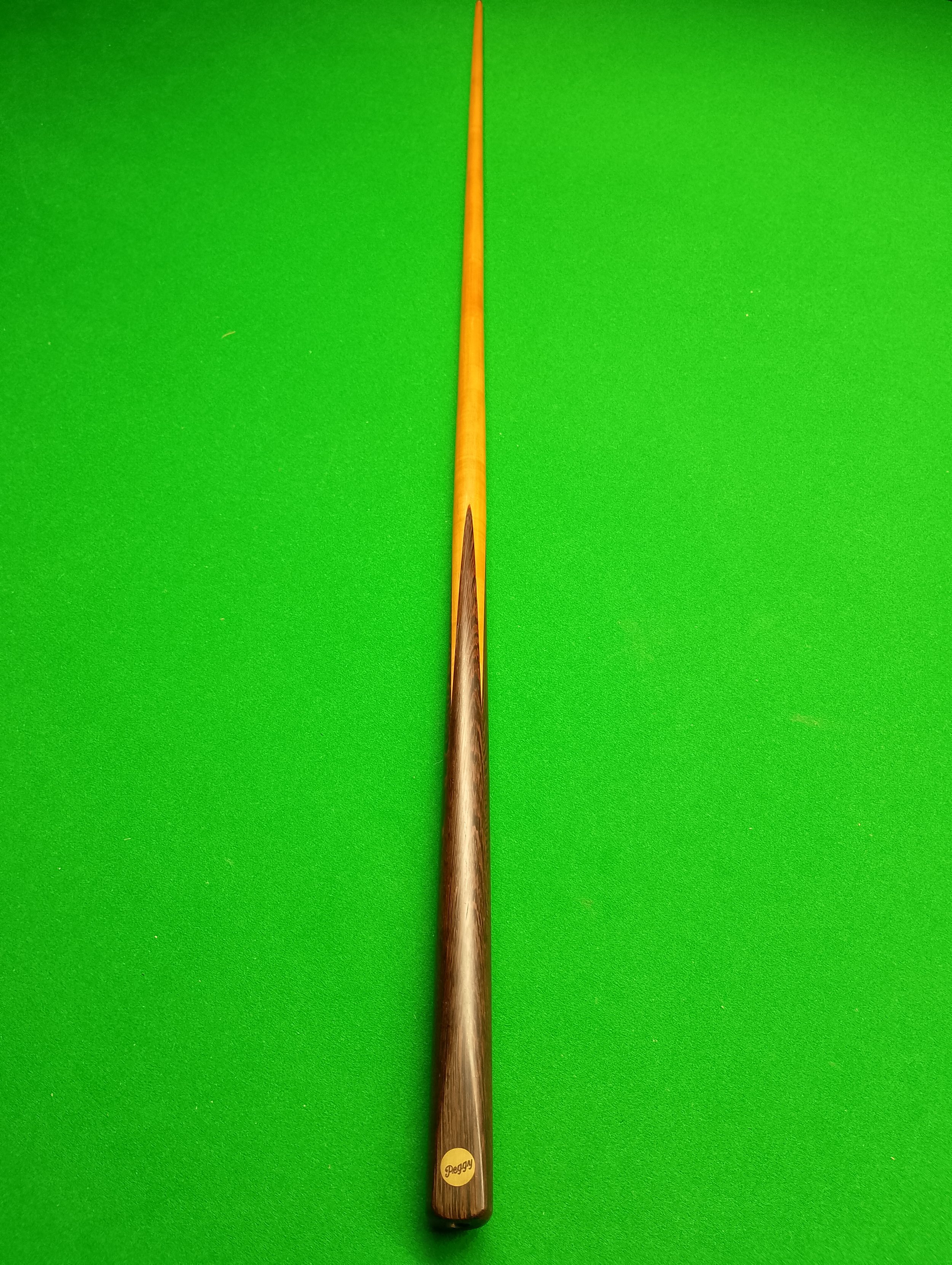 A cue stick for playing billiards or pool lying on a green pool table.