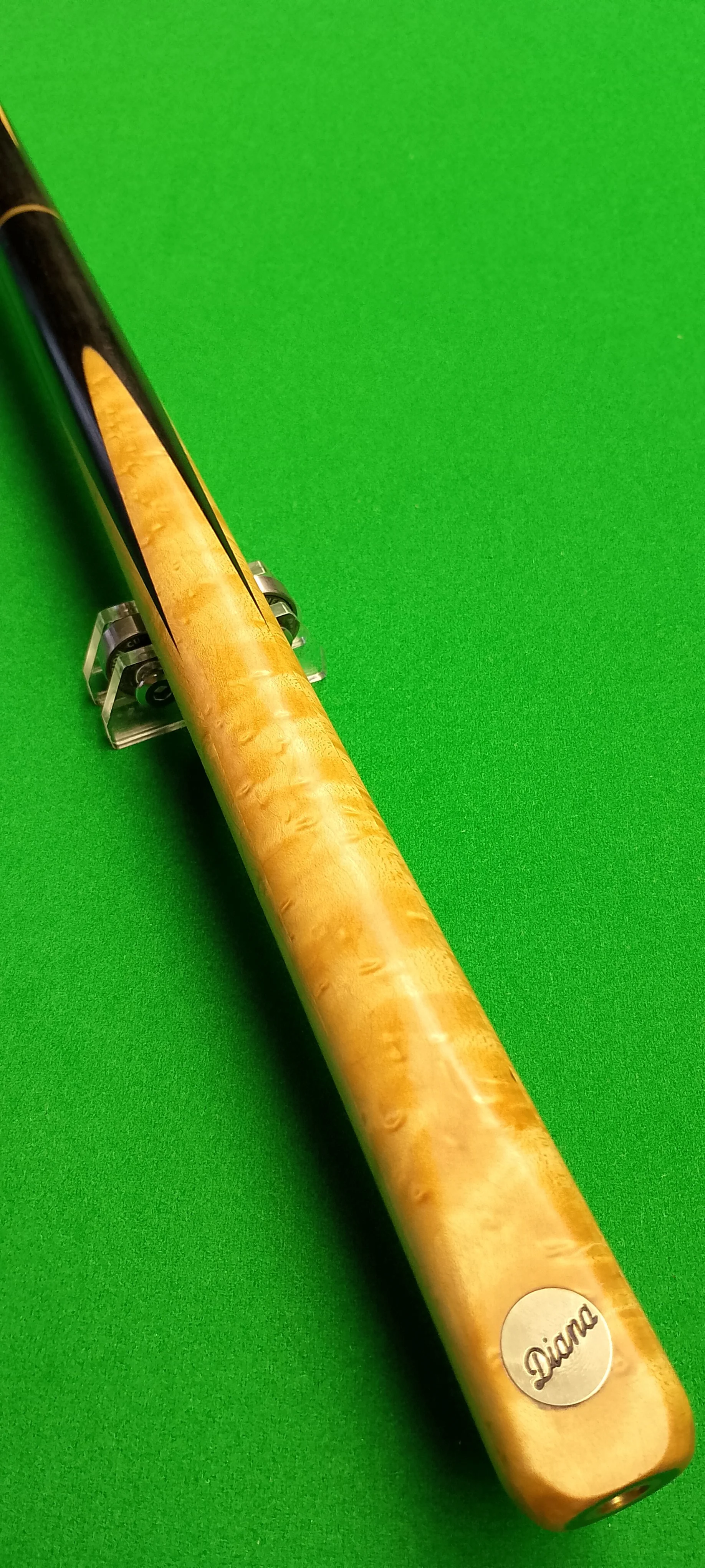 A pool cue stick resting on a small transparent stand on a green pool table surface.