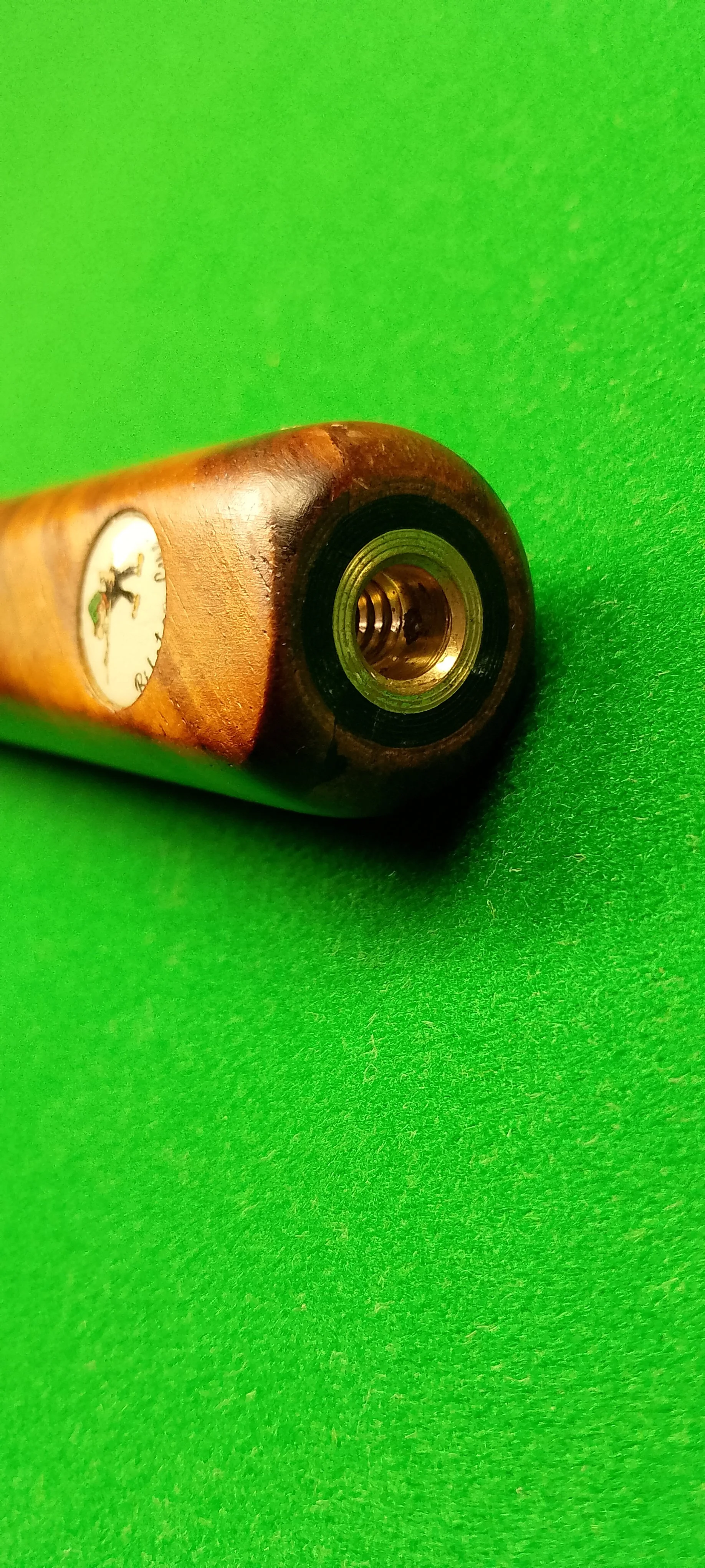 Close-up of a wooden cigar humidor with a brass rim, resting on a green felt surface.