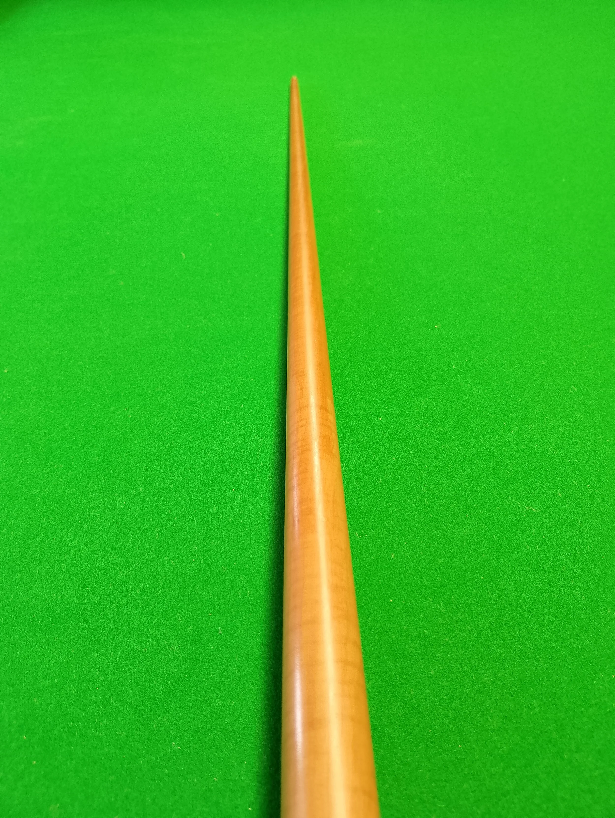 Close-up of a cue stick on a green pool table.