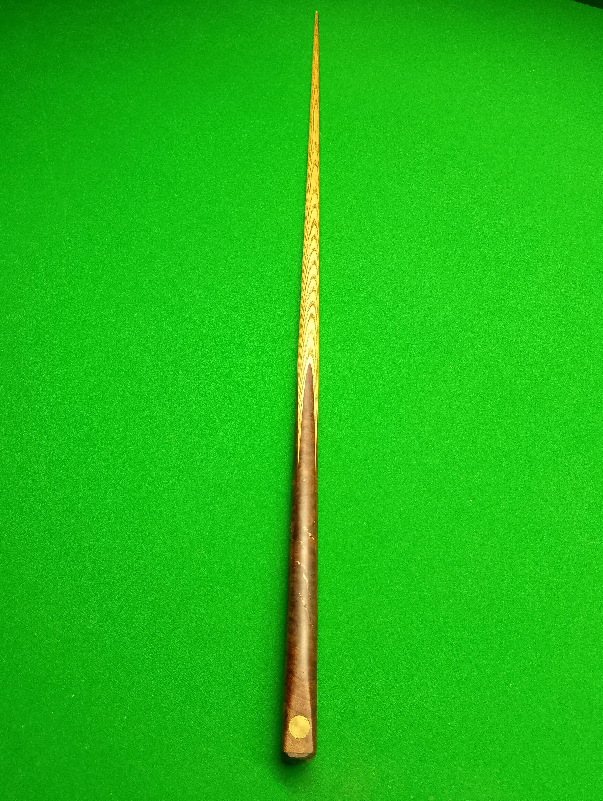 A long wooden cue stick placed on a green billiard table.
