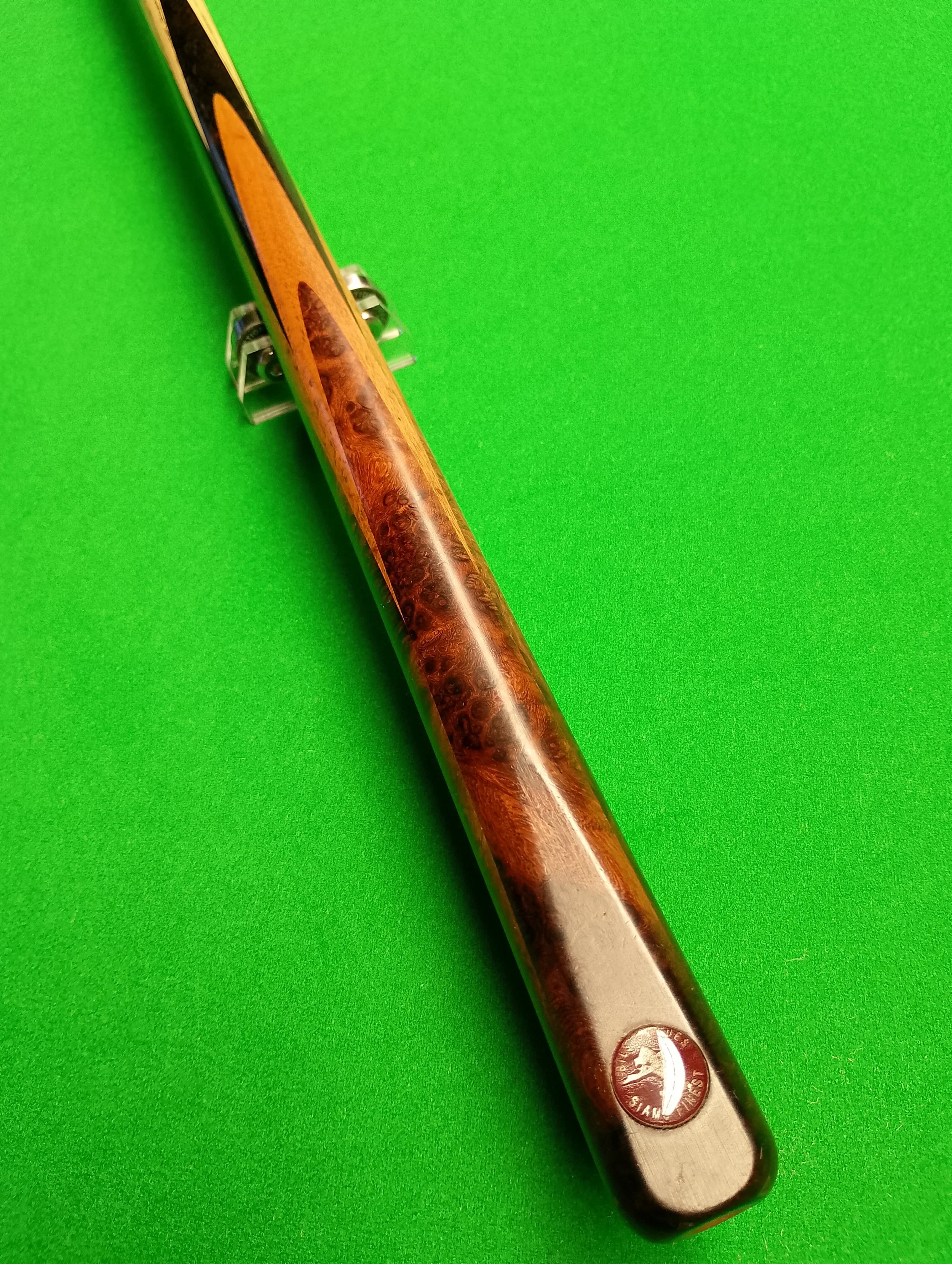 A snooker cue stick with a wooden and black design on a bright green surface.