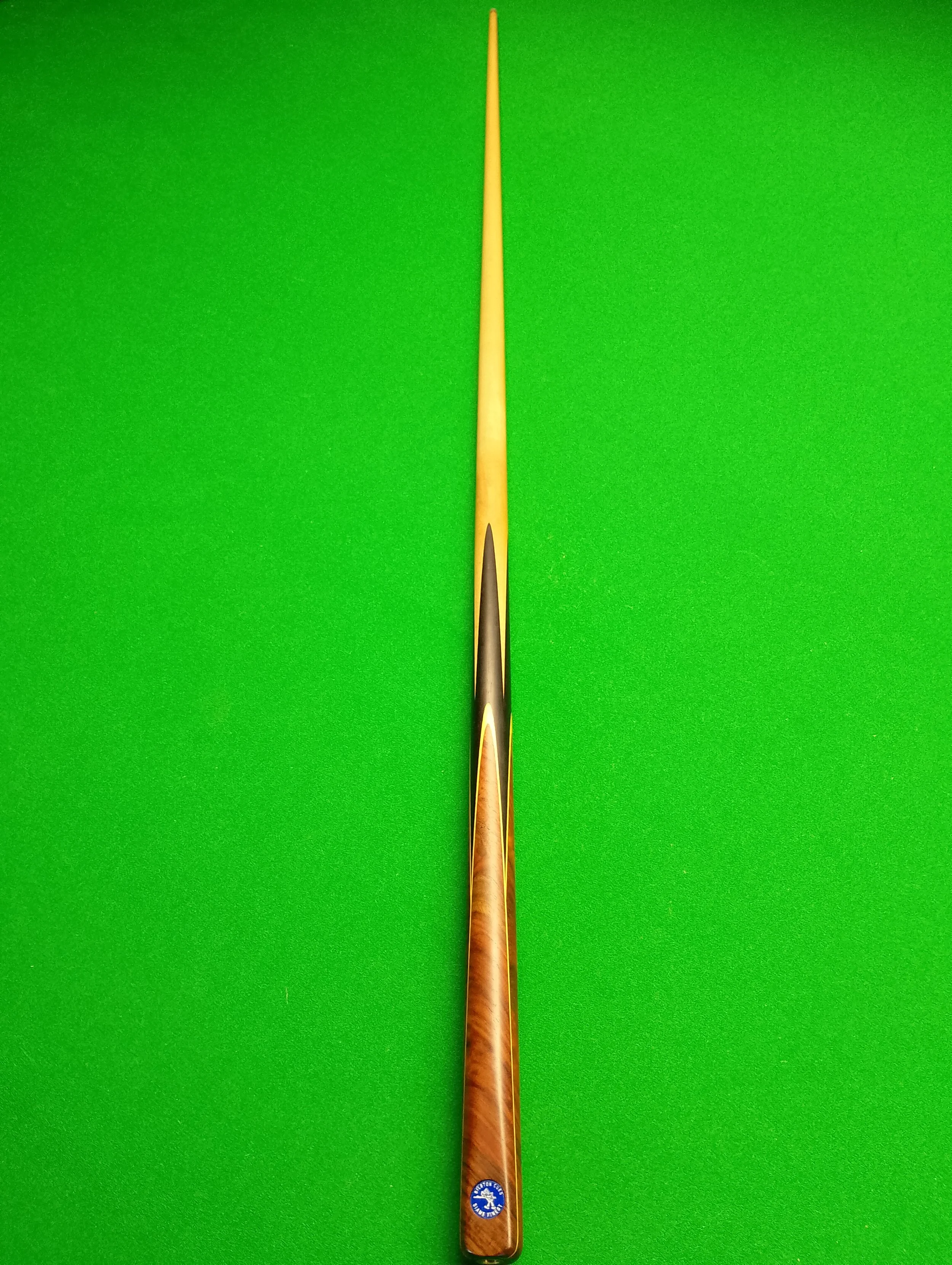A single billiard cue stick on a green pool table.