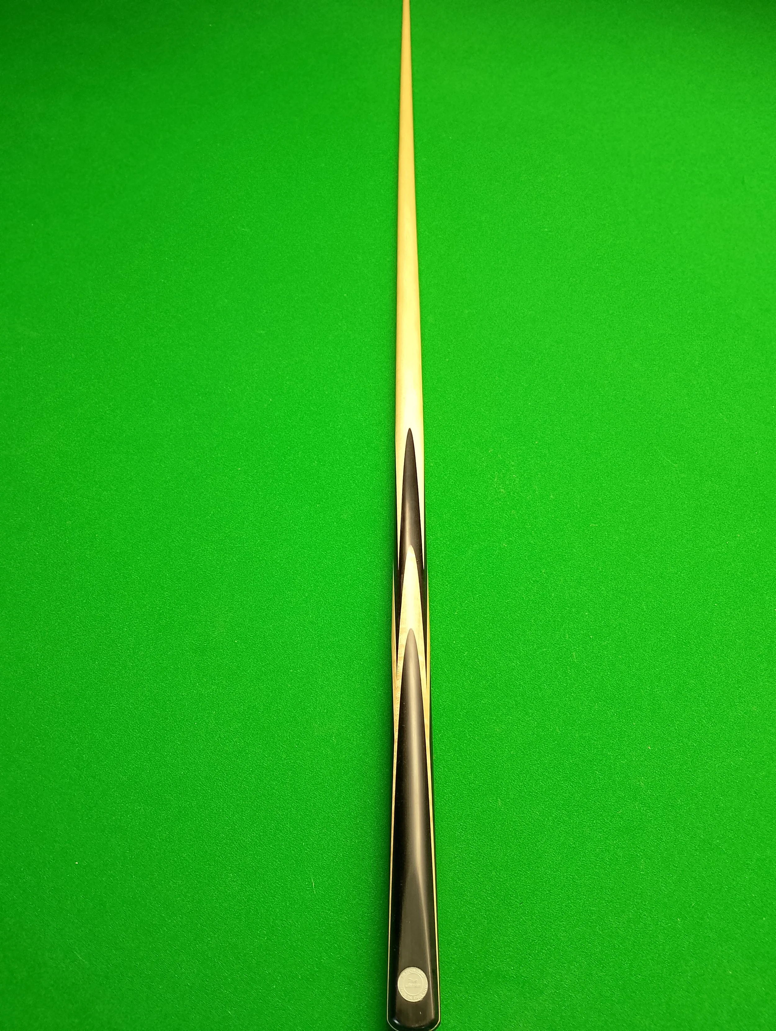 A cue stick on a green pool table cloth, positioned vertically in the center of the image.