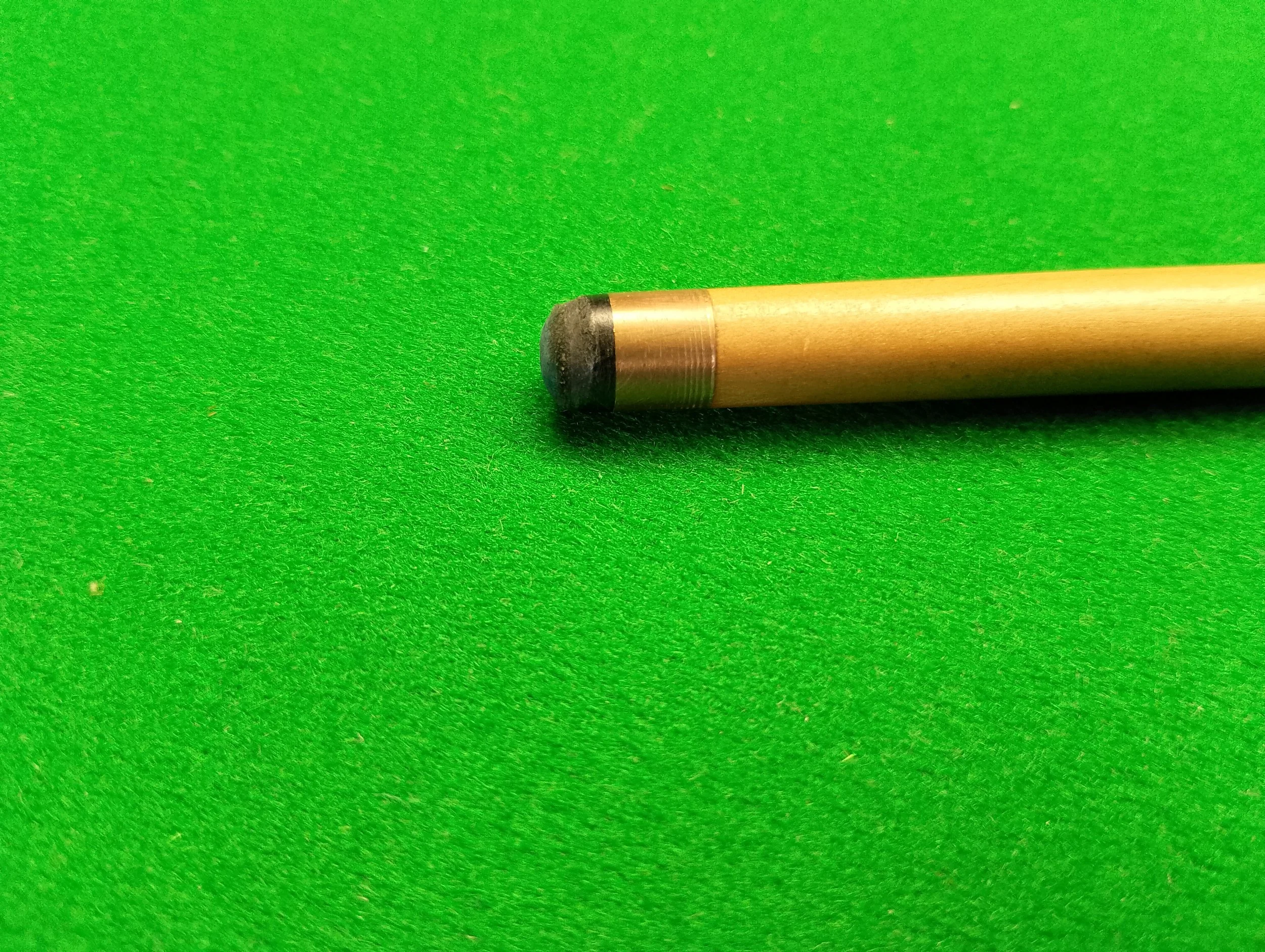 Close-up of a billiard cue tip on a green felt table.