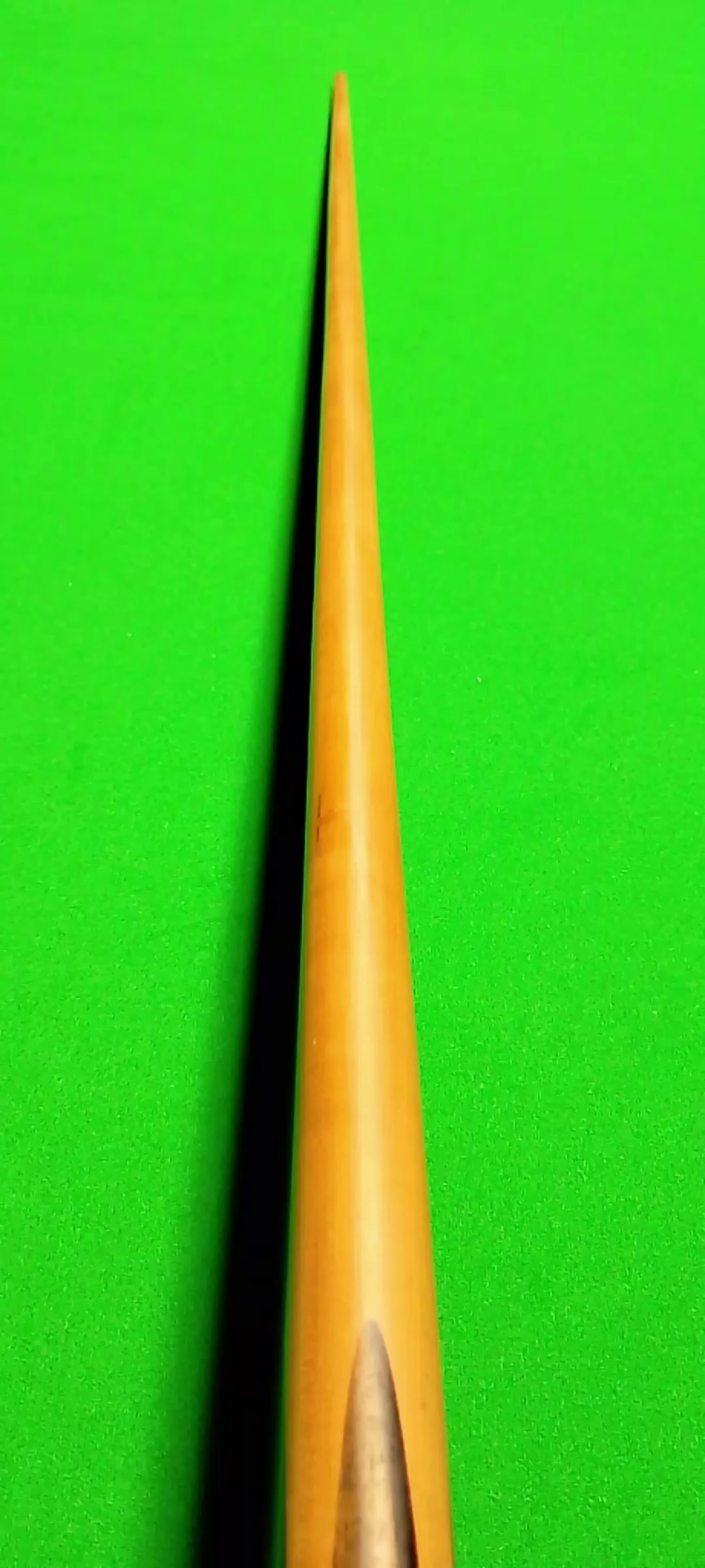 Close-up of a cue stick on a green billiards table.