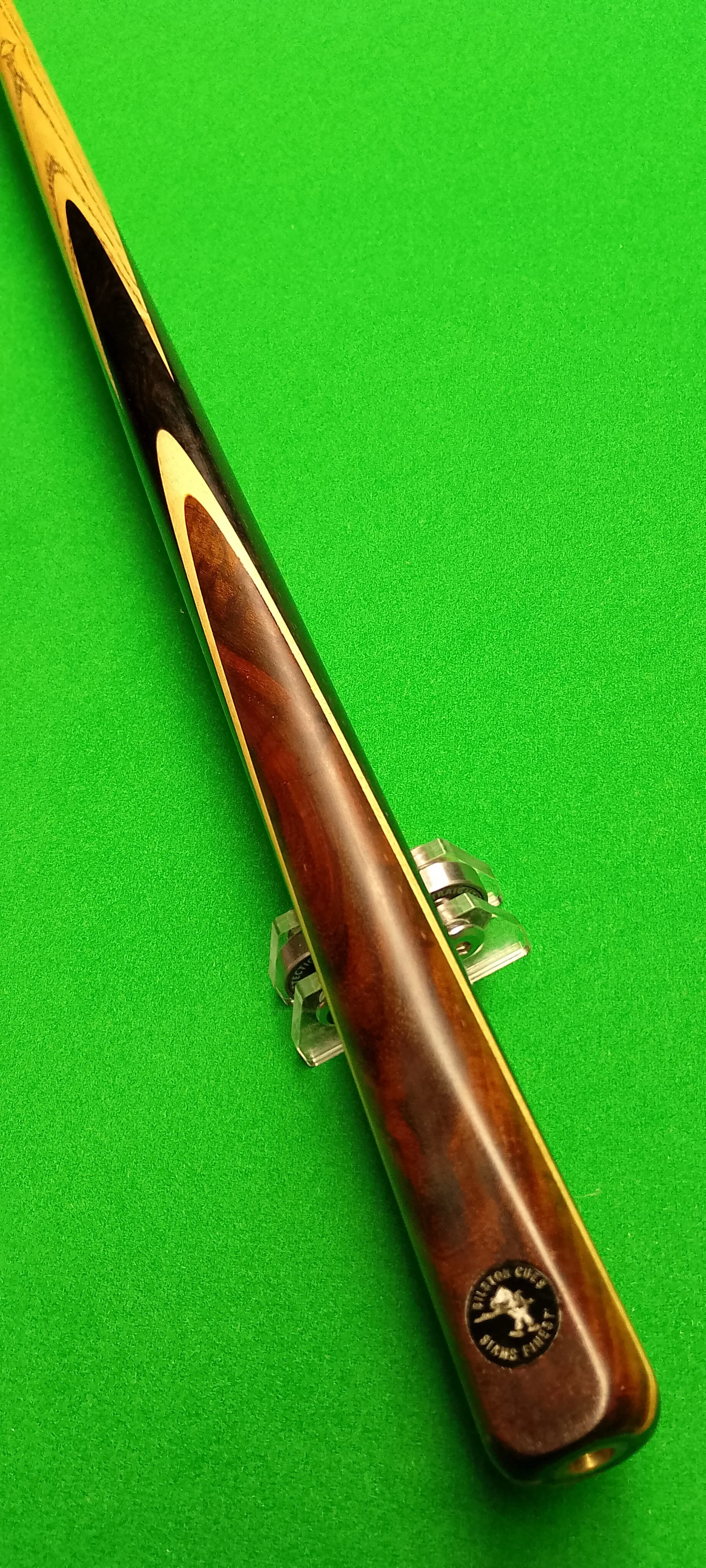 A pool cue with a wooden finish on a green pool table.