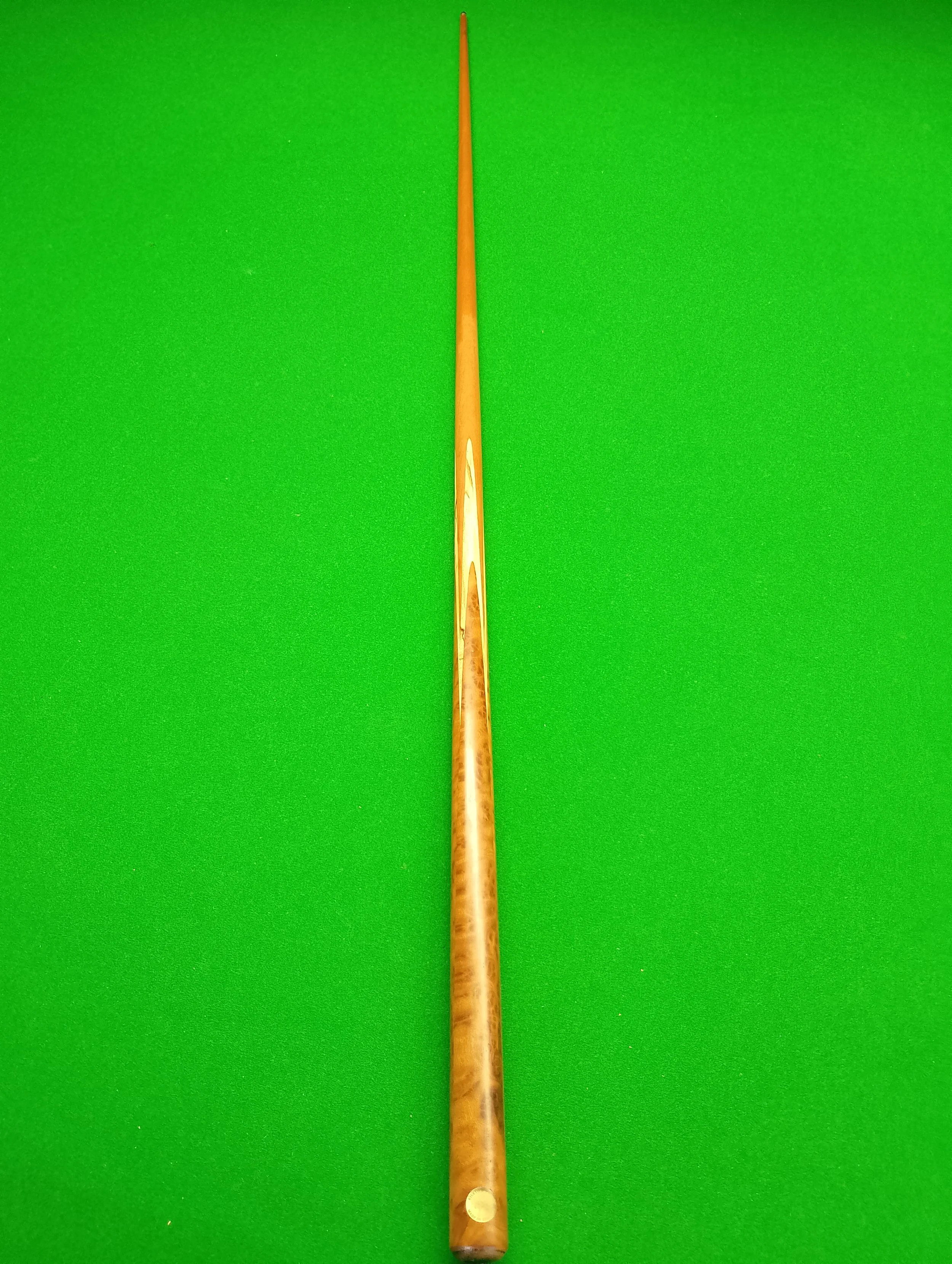A cue stick placed on a green billiards or snooker table.