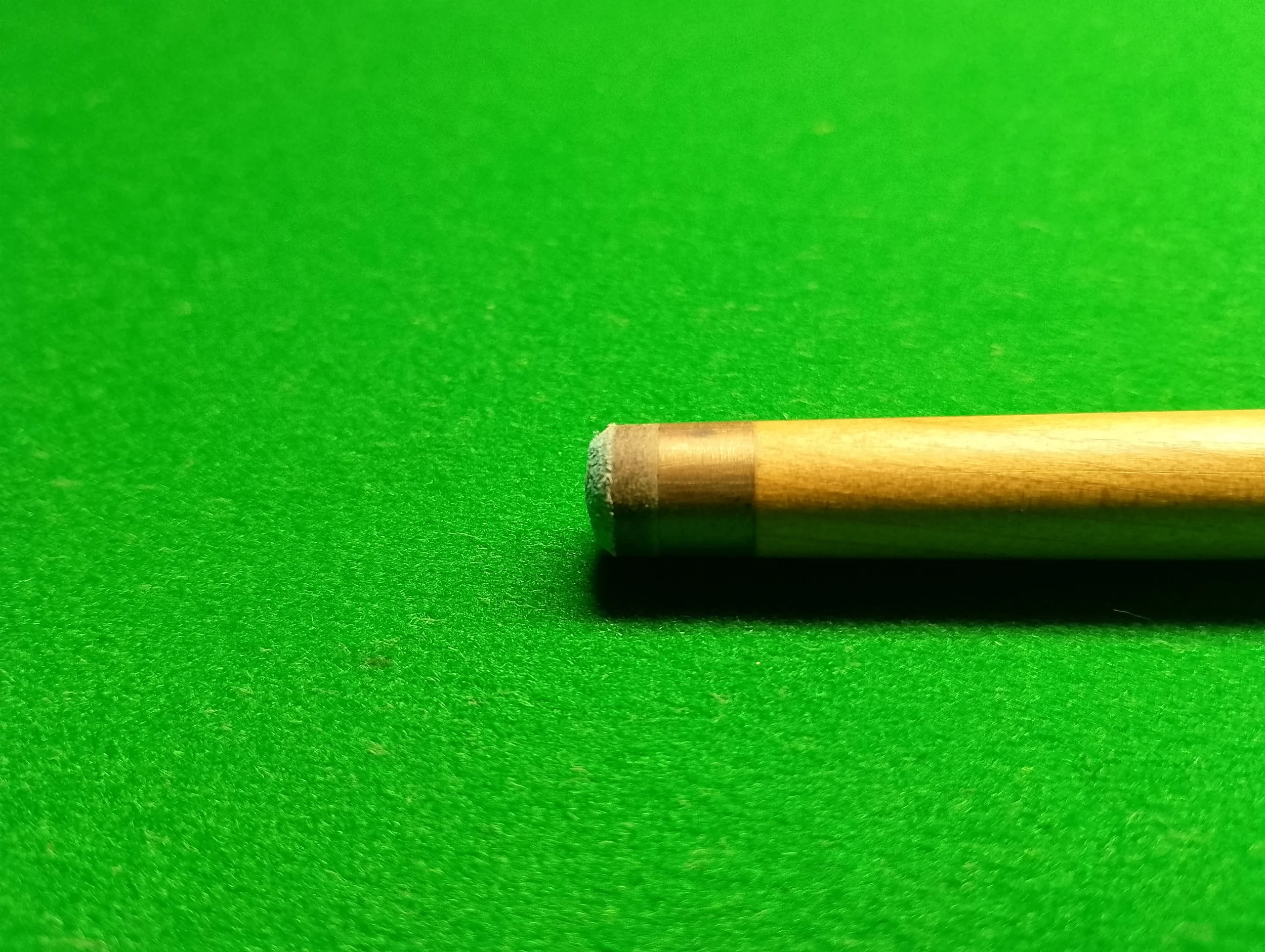 Close-up of a wooden chalk in a green chalkboard surface.