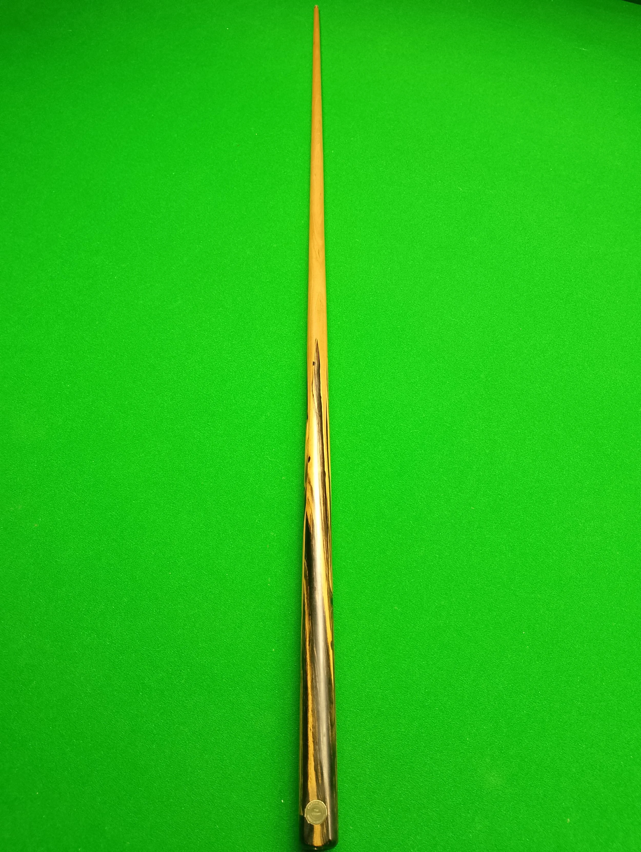 A wooden cue stick resting on a green pool or billiard table.