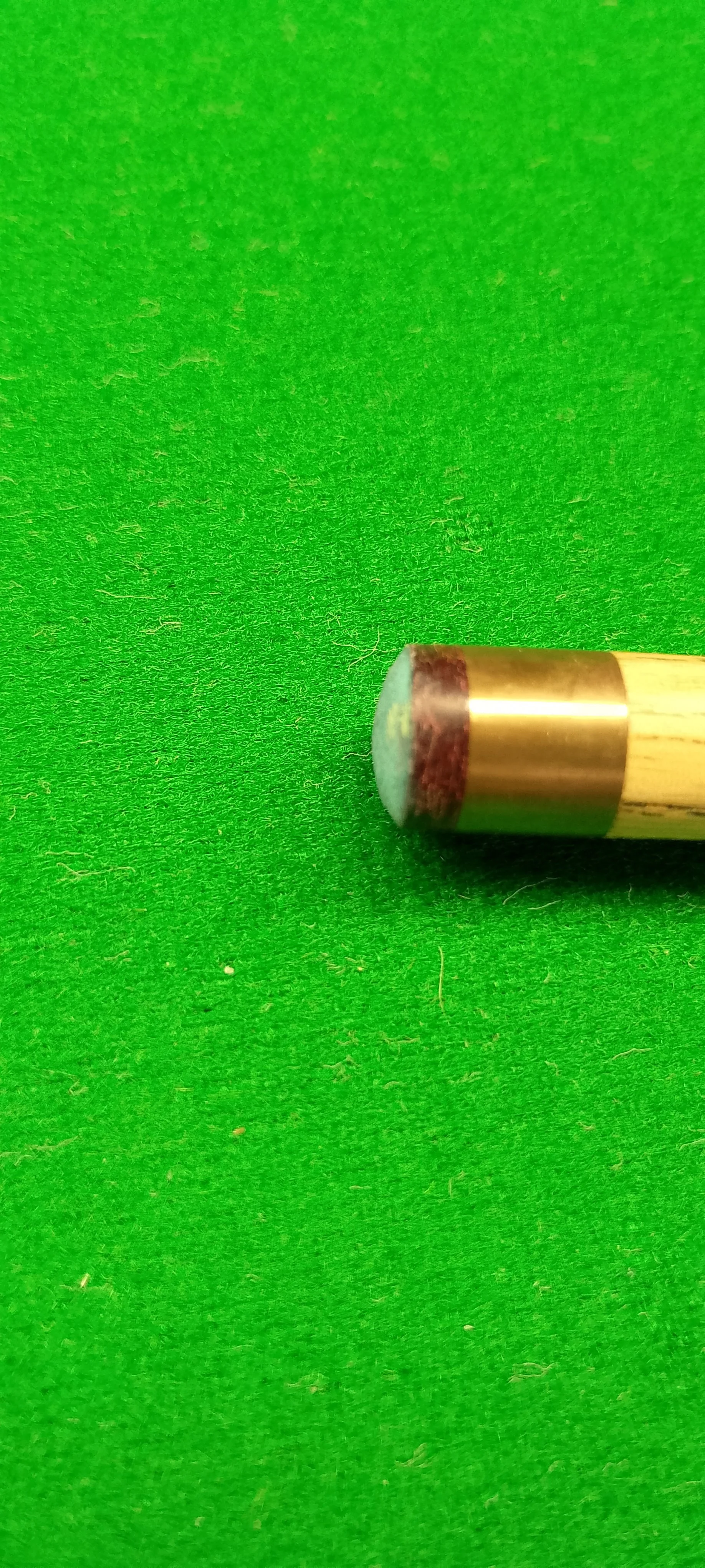 Close-up of a pool cue tip on a green felt billiard table.