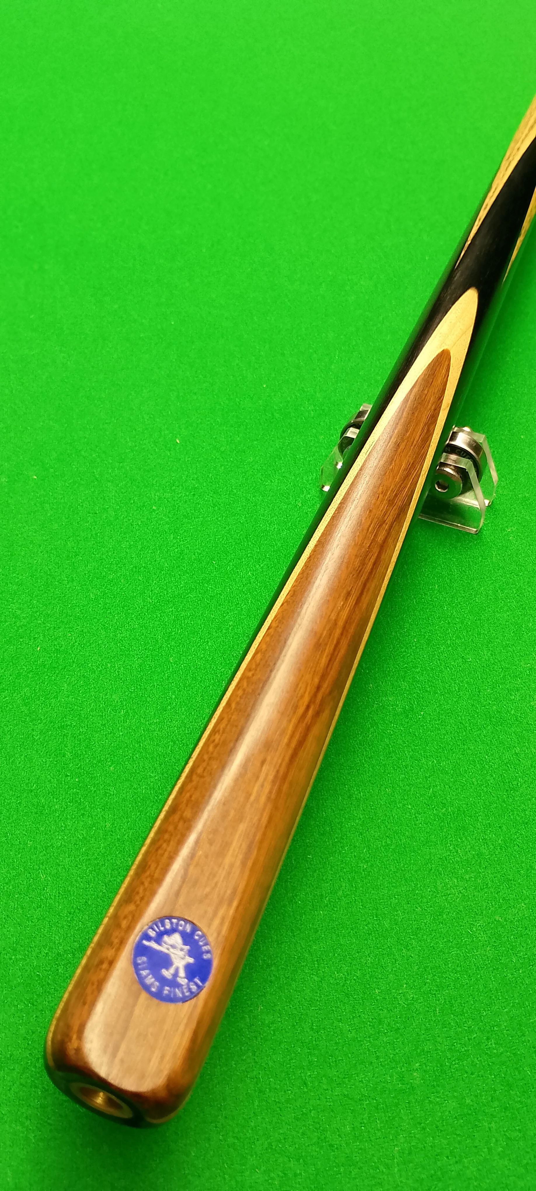 A billiards cue stick placed on a green pool table