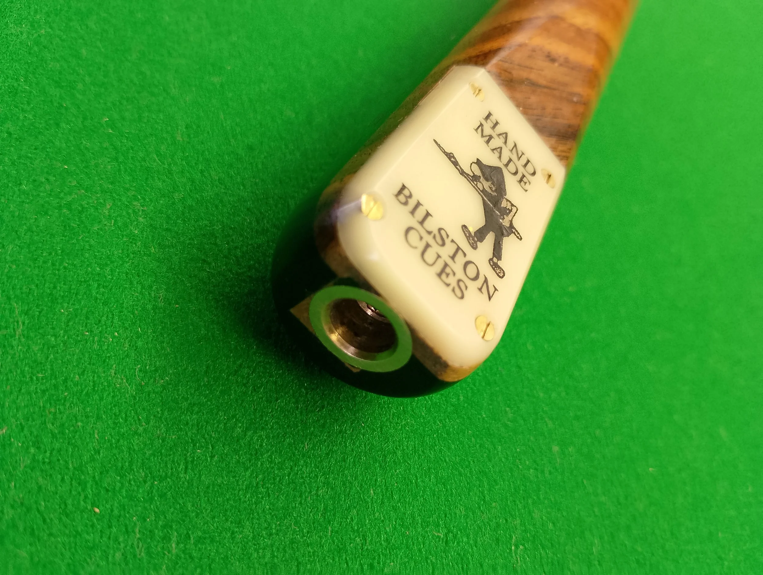 A billiards cue rest with a sign that reads 'Hand Made Billiard Cues' and features a person aiming a cue stick.