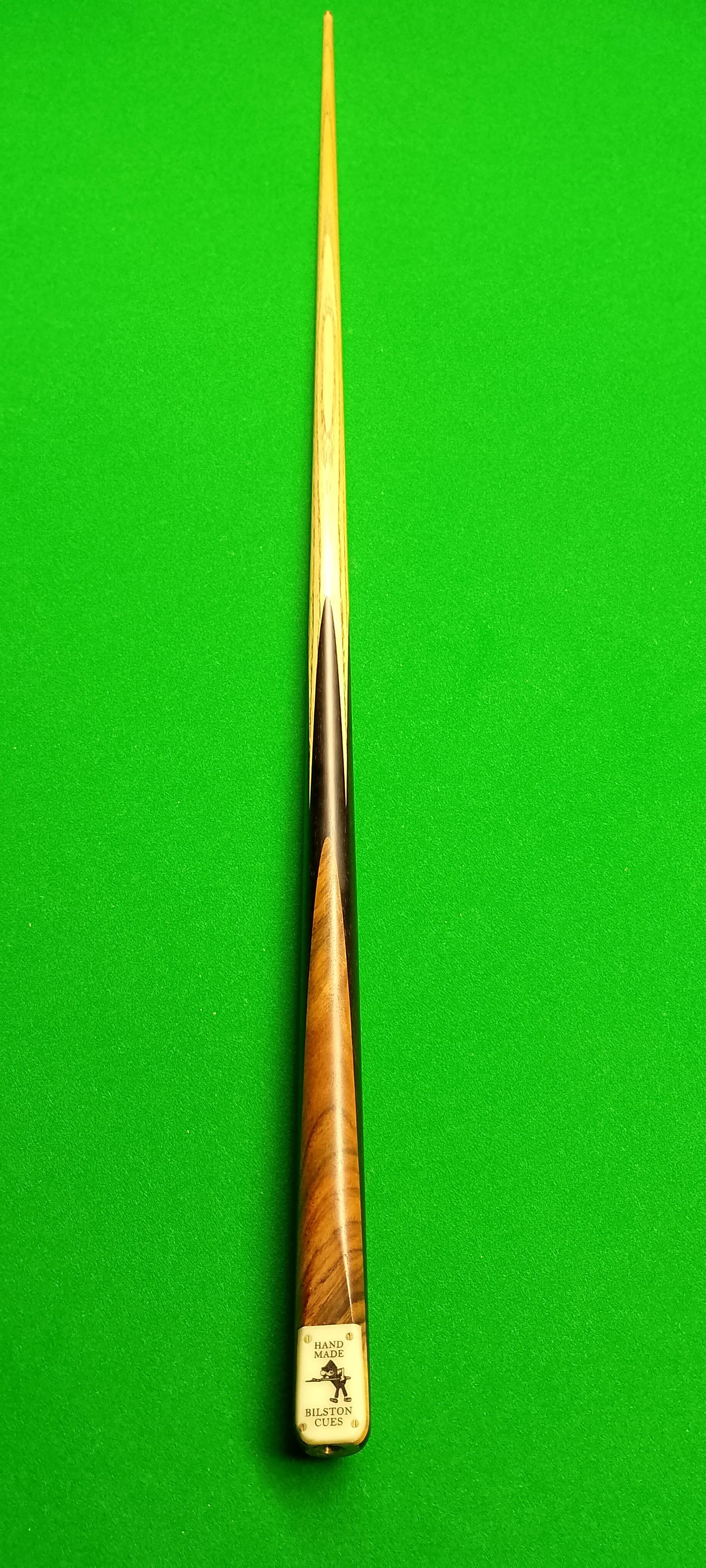A billiard cue stick placed vertically on a green pool table felt.