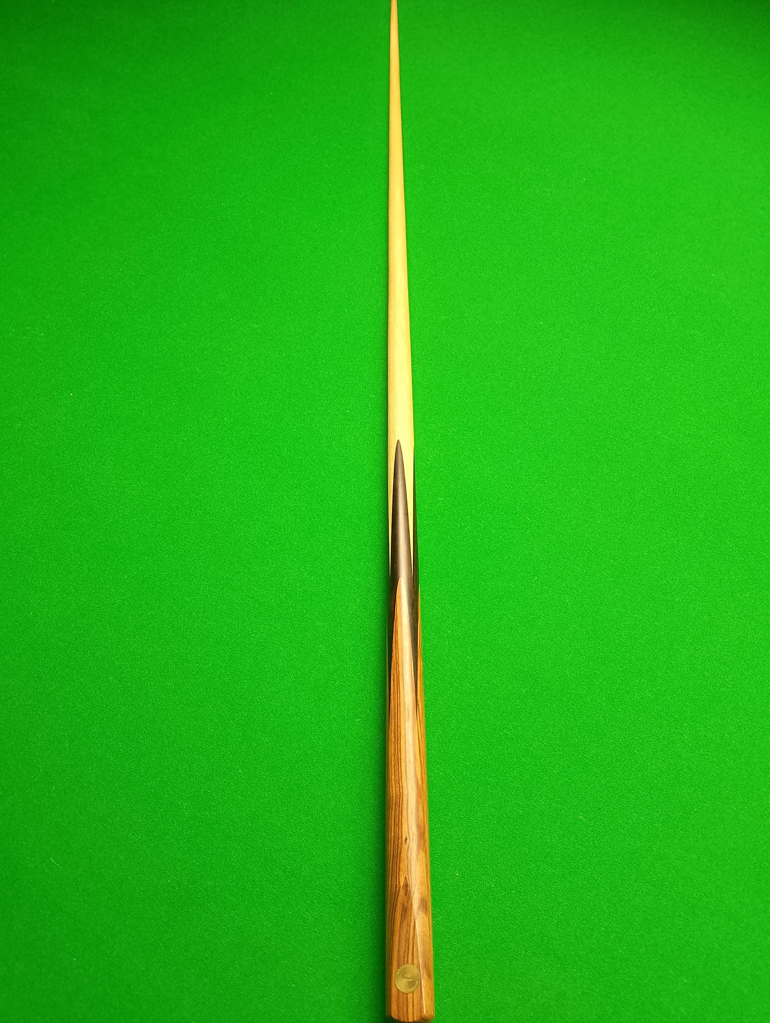 A wooden snooker cue resting on a green pool table surface.