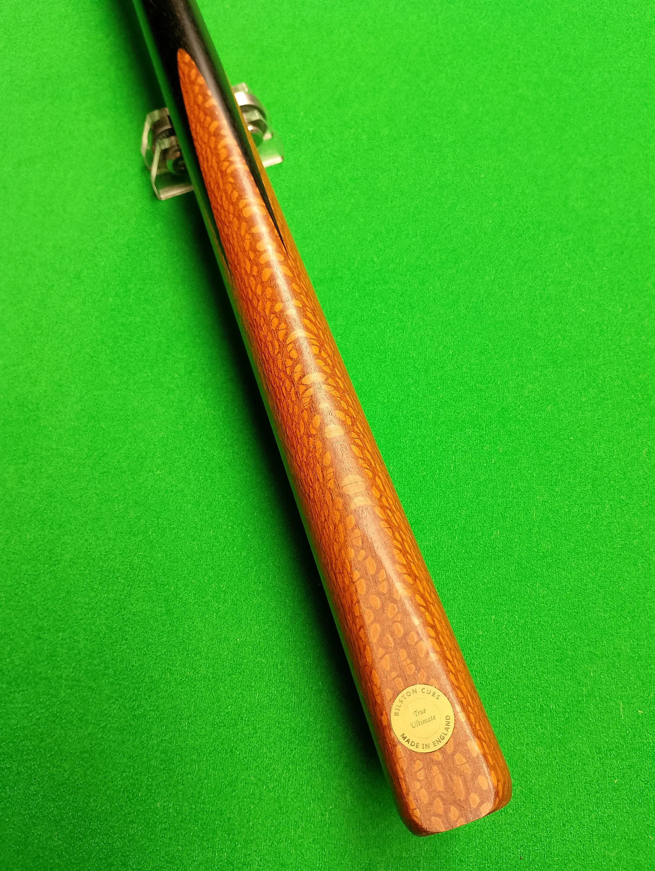 Pool cue with a wooden finish on a green felt pool table.