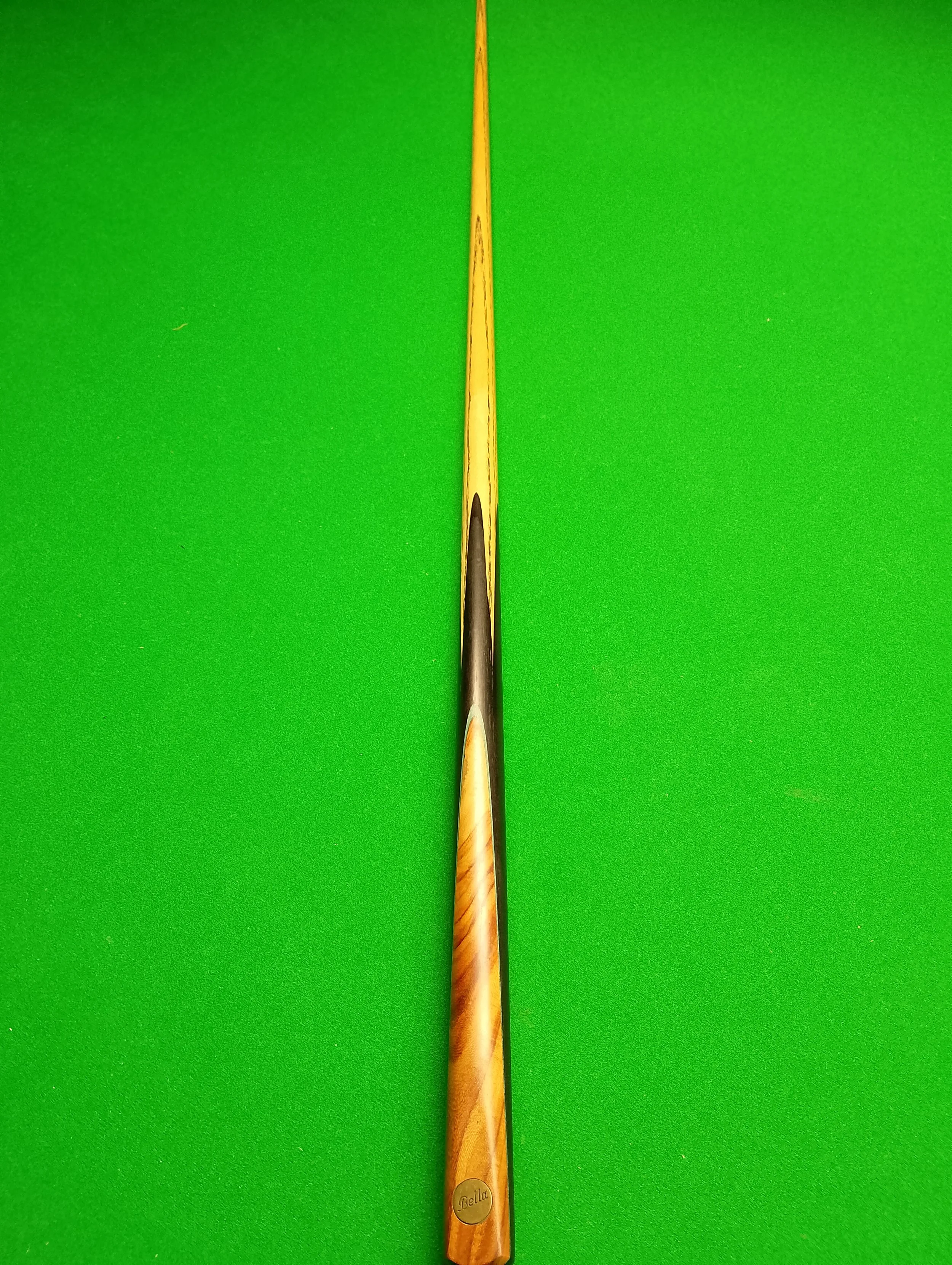 A pool cue stick laying on a bright green pool table surface.