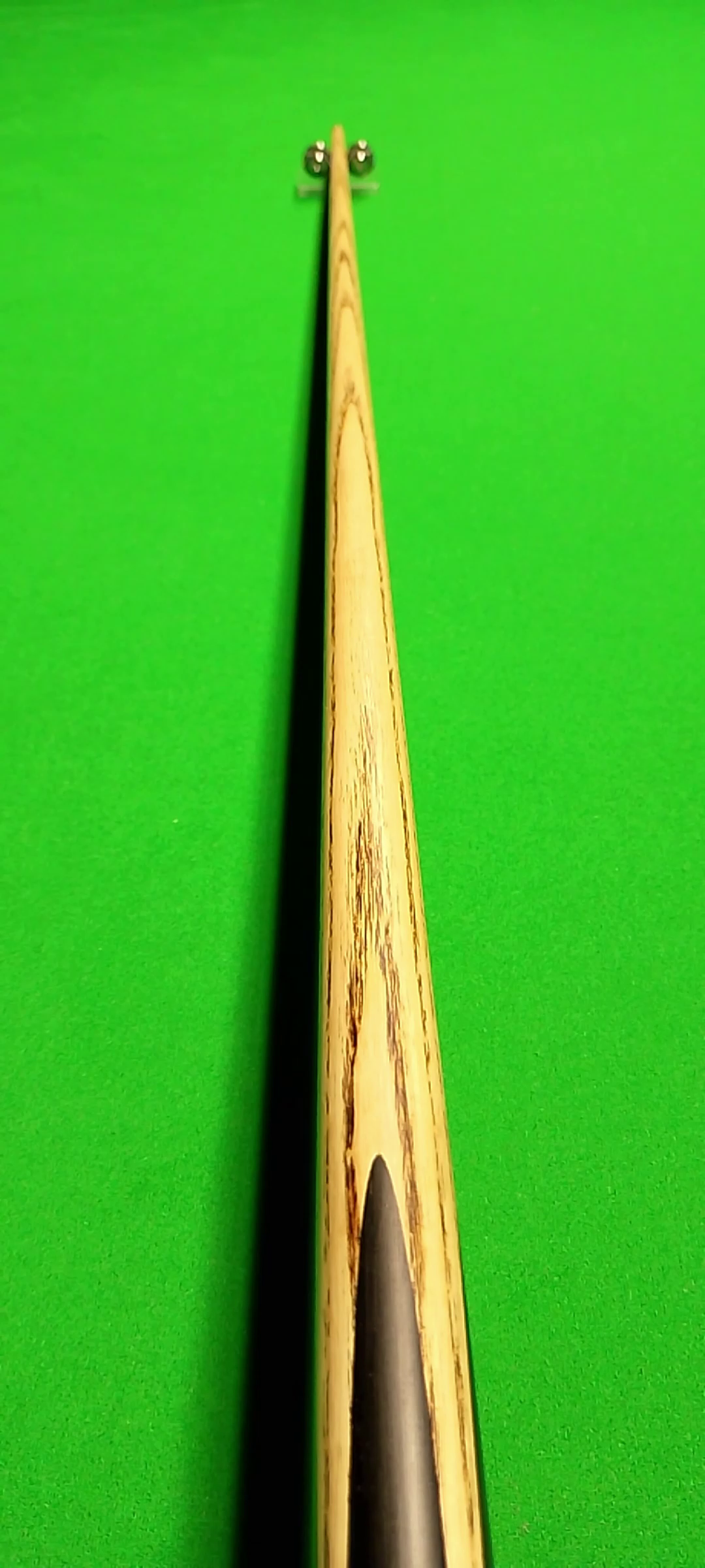 Close-up of a snooker cue stick on a green pool table.