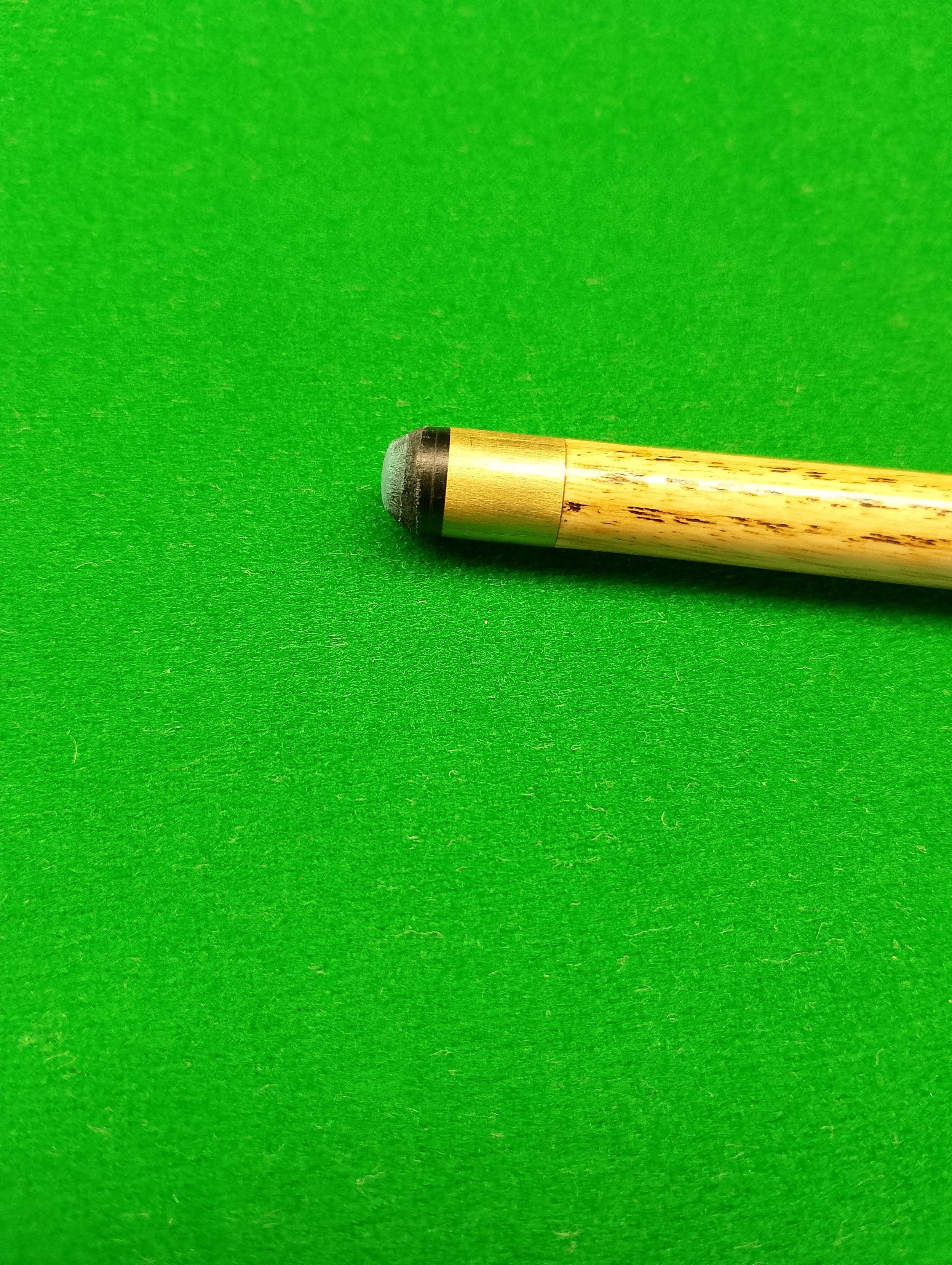 Close-up of a billiard cue stick on a green felt table.