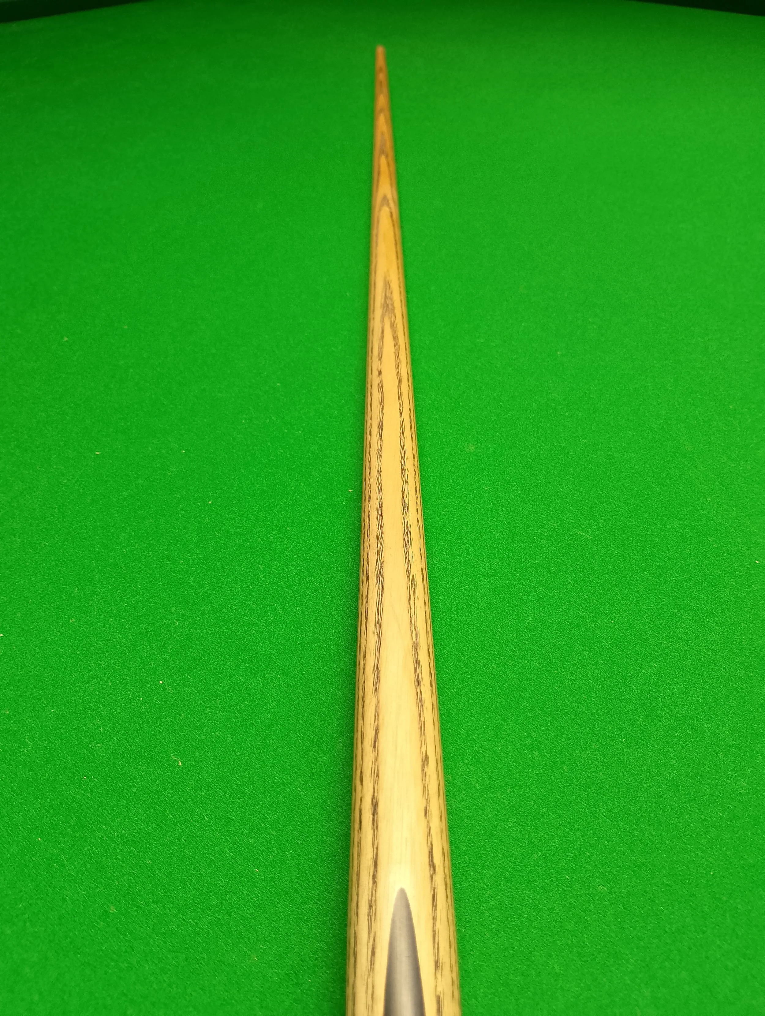 Close-up of a snooker cue stick placed on a green snooker table.
