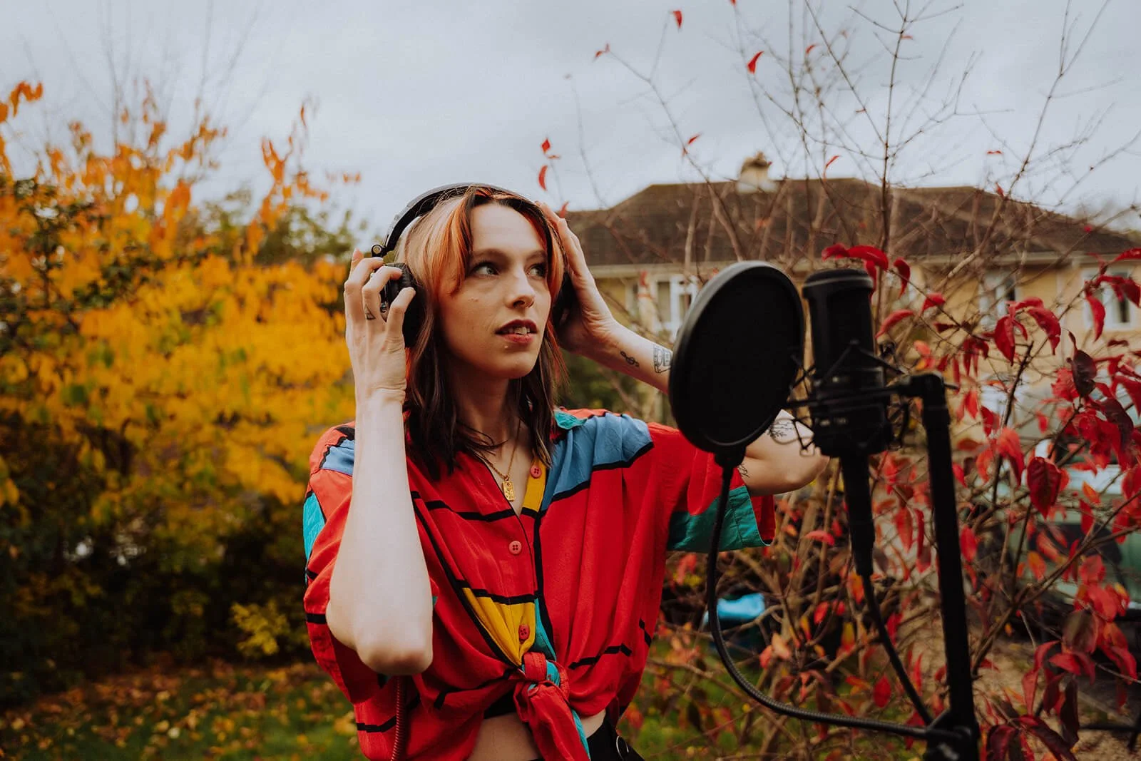 Amelle recording in a home studio with a microphone and headphones for custom wedding song recordings.