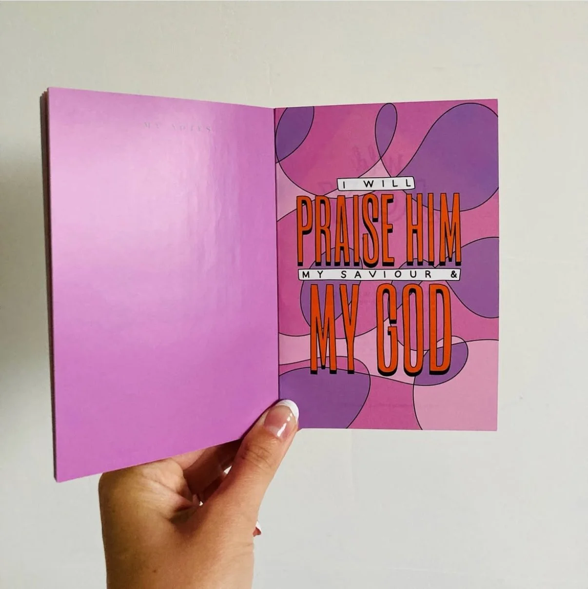 Open pink and purple booklet with the words 'I will praise him my savior & my God' on the right page.