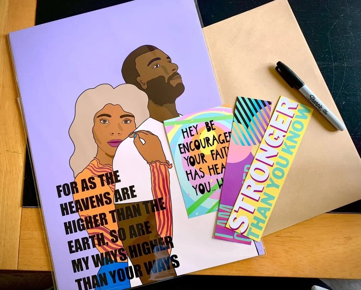 Open book with illustrated woman and man, with motivational and religious quote cards, a Sharpie marker, on a desk.