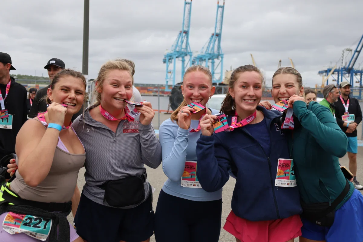 Photo of five people after the run biting their medals