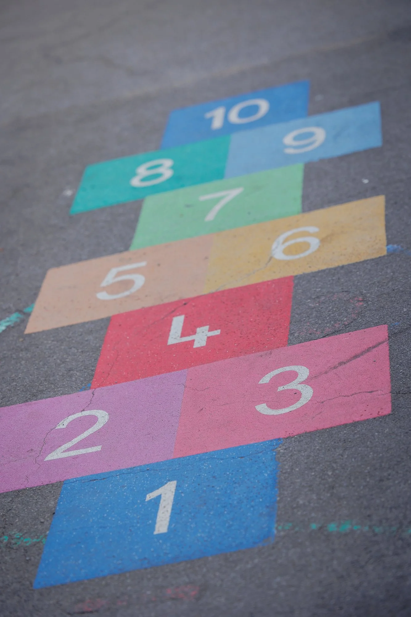 Colourful hopscotch chalk outline painted on asphalt with numbers from 1 to 10.