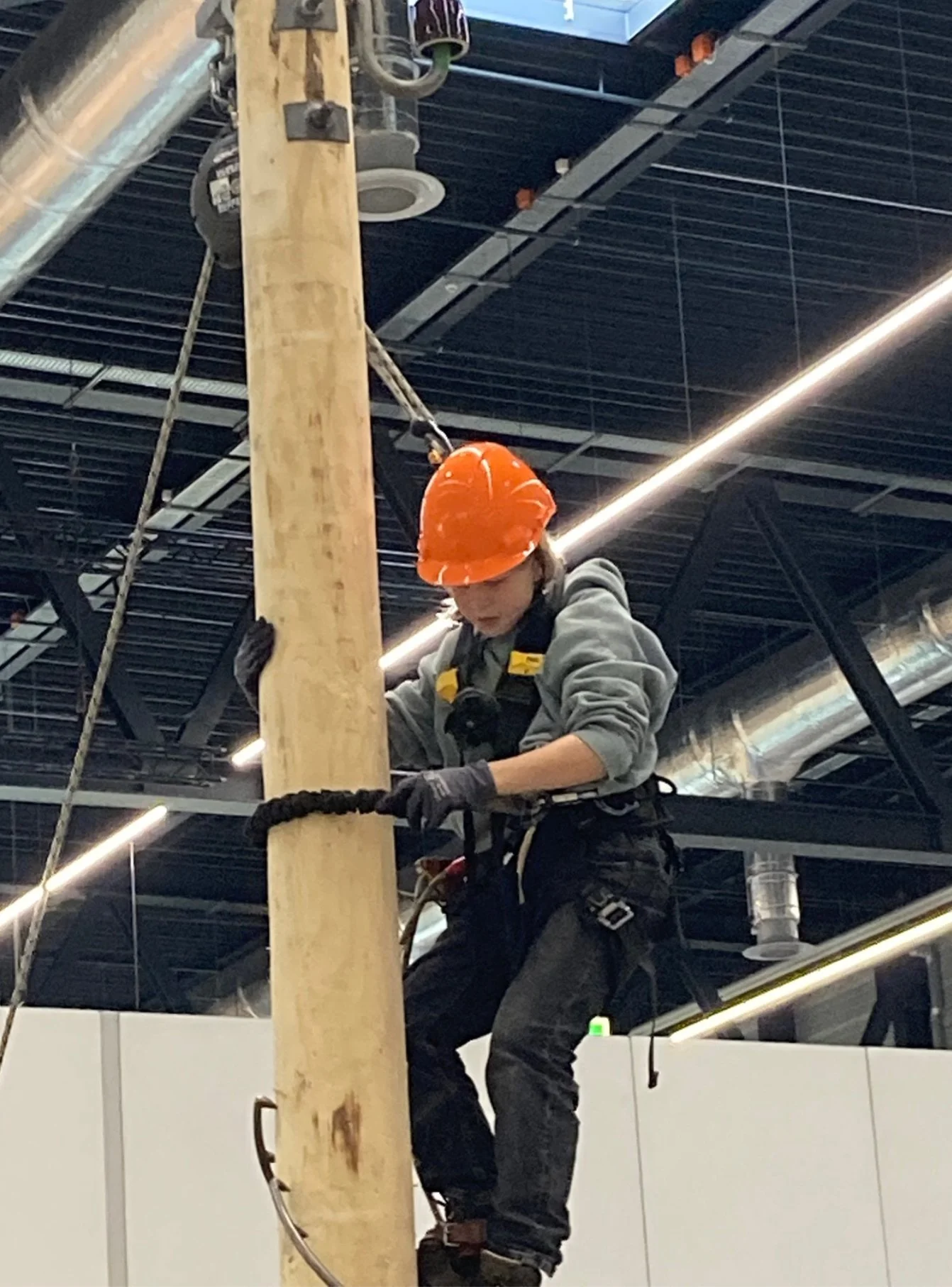Eine Schülerin mit rotem Helm klettert bei einem Aktionstag auf einen Holzpfahl