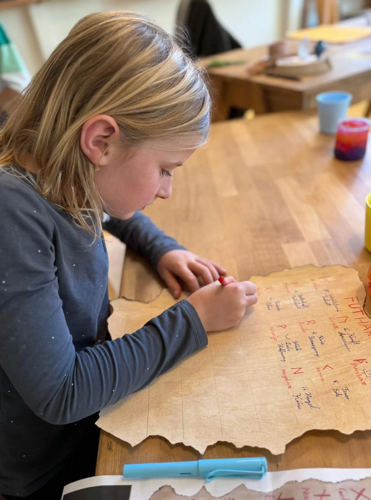 Ein Kind zeichnet Runen auf ein Pergamentpapier