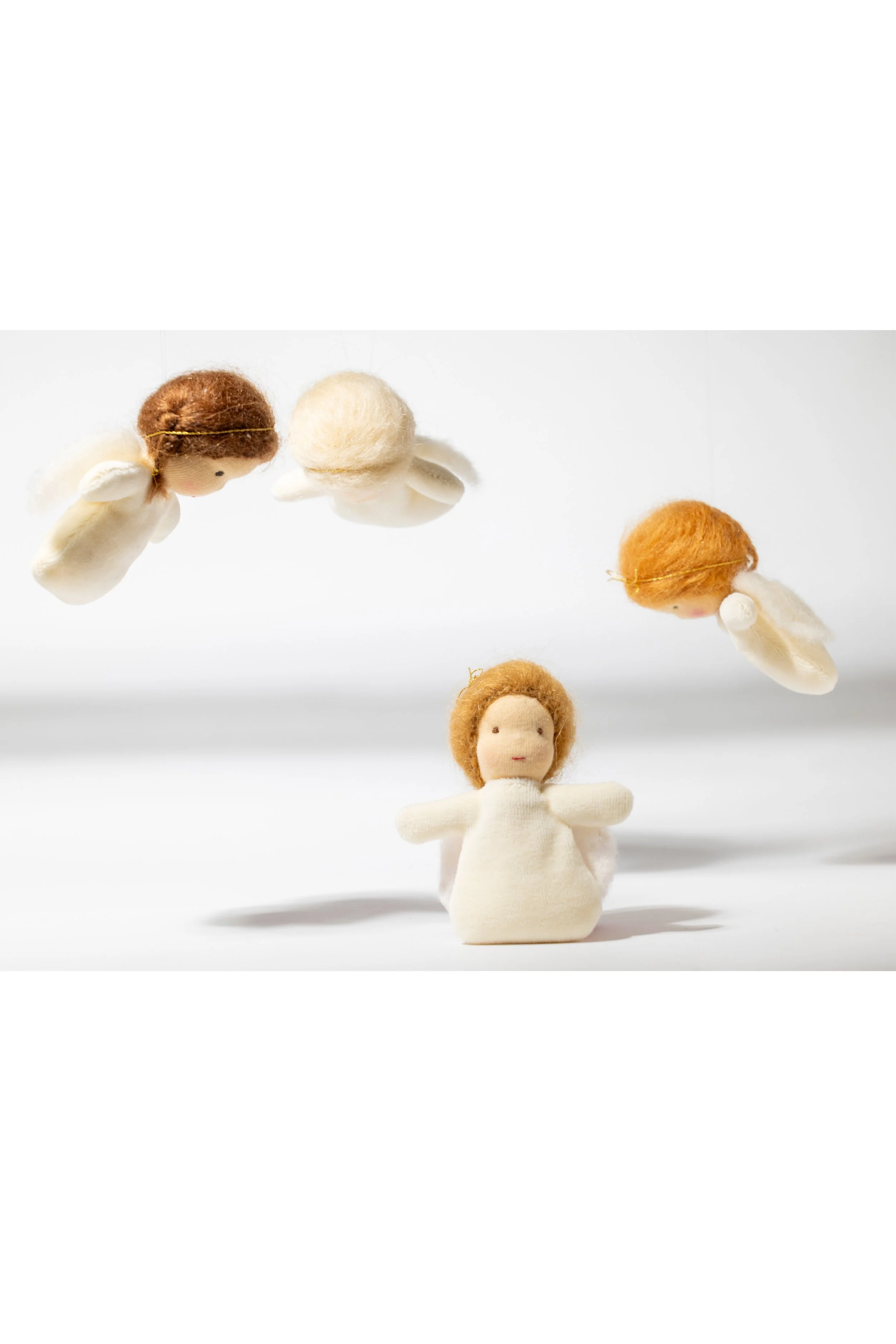 Wolkenengel aus Stoff, die fliegen, über einer sitzenden Stoffengel auf weißem Hintergrund.Waldorf-Art.