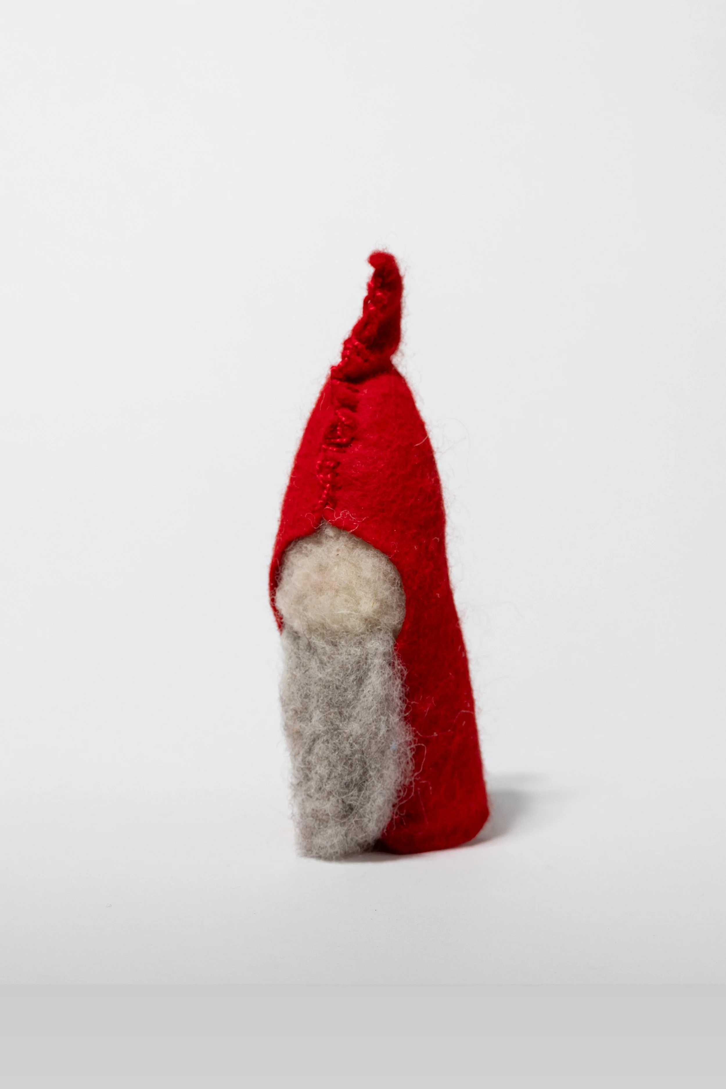 Ein kleiner Filz-Zerg mit roter Mütze und weißem Bart auf weißem Hintergrund.