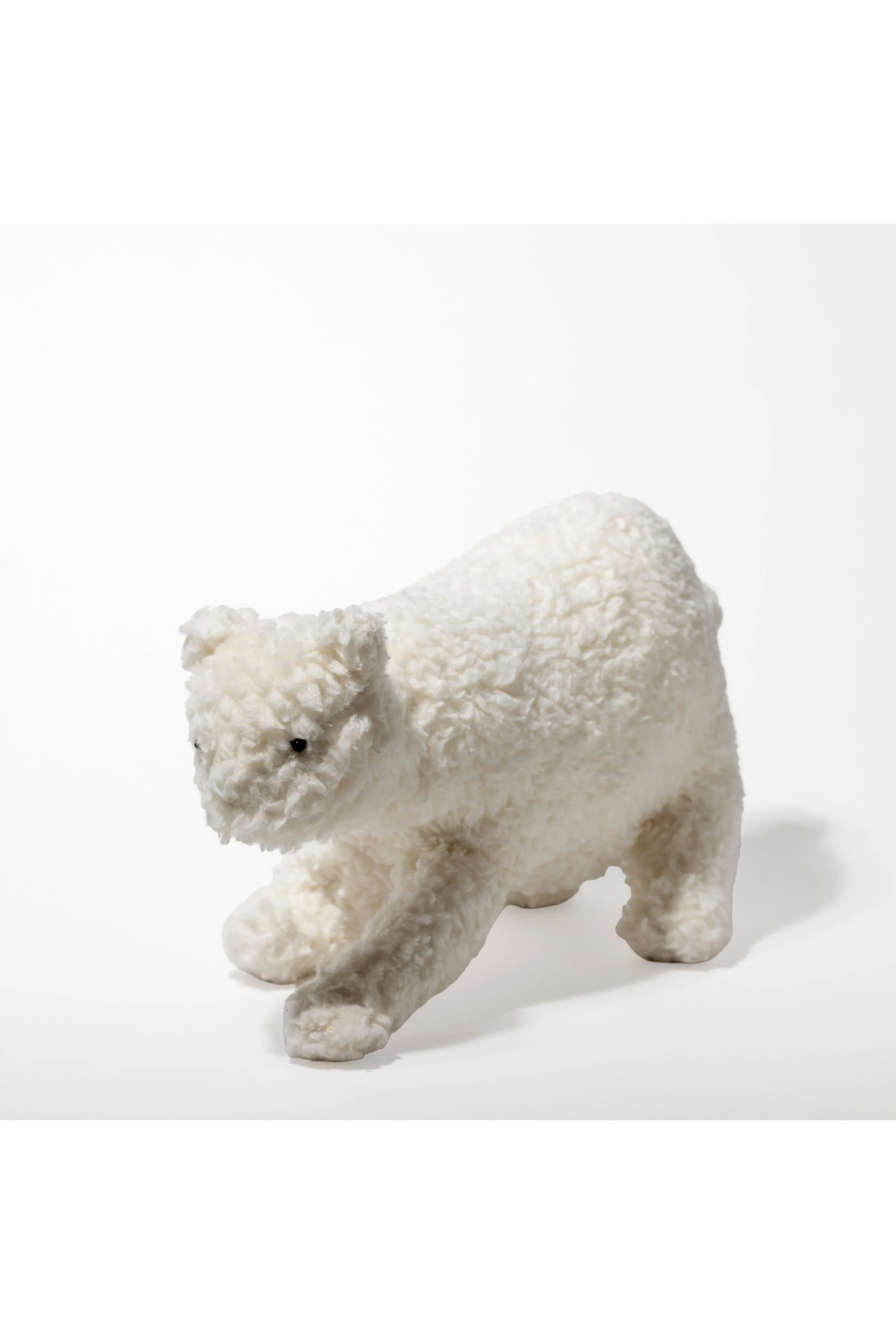 Handgefertigtes Plüschtier eines weißen Bären auf weißem Hintergrund.