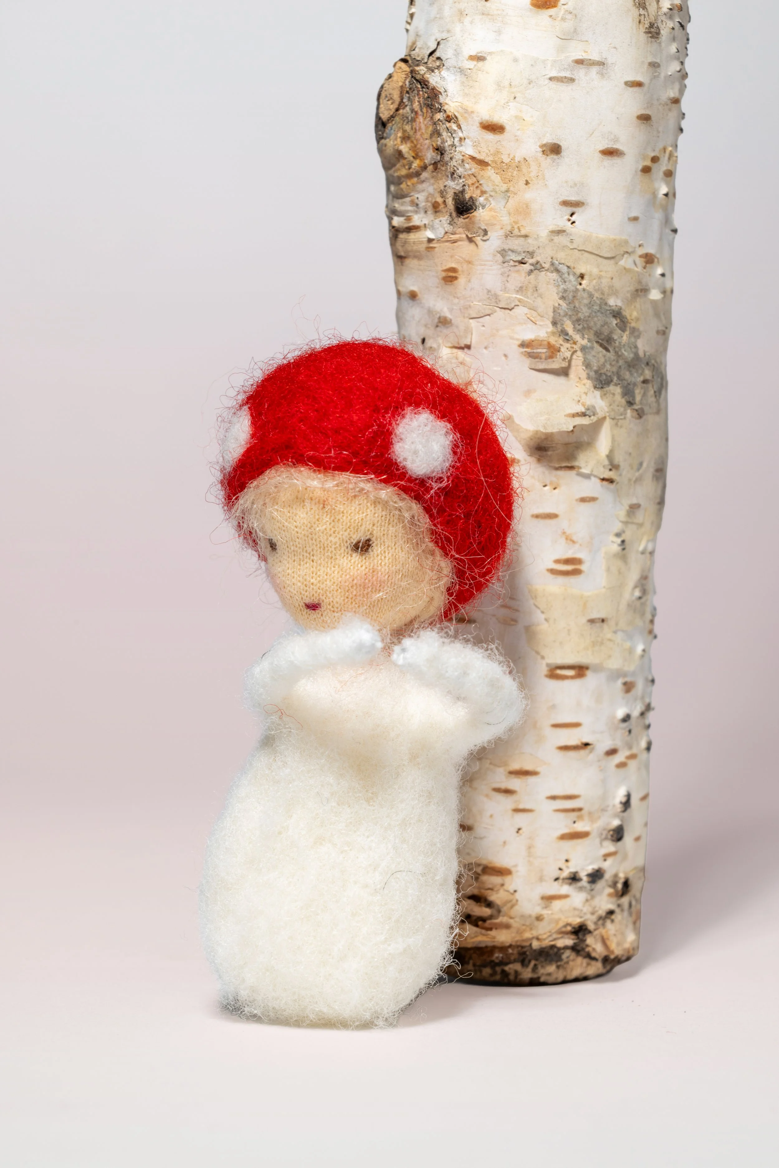 Filzfigur Jahreszeitenpüppchen, Fliegenpilz, nach Waldorf-Art, Handgefertigtes Unikat, und Birkenstamm im Hintergrund.