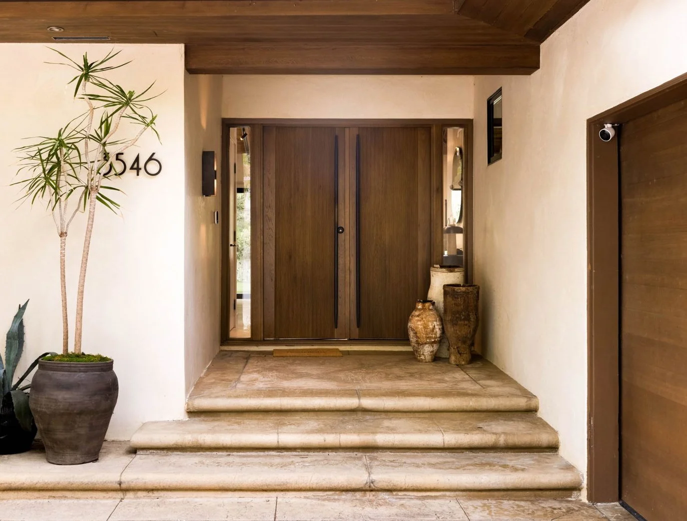 Welcome to our Canyon Ranch House. Upon entering, you're greeted by a completely reimagined front entry featuring a custom wood door with sidelights. The door showcases a beautiful reeded wood detail, complemented by custom elongated brass pulls that
