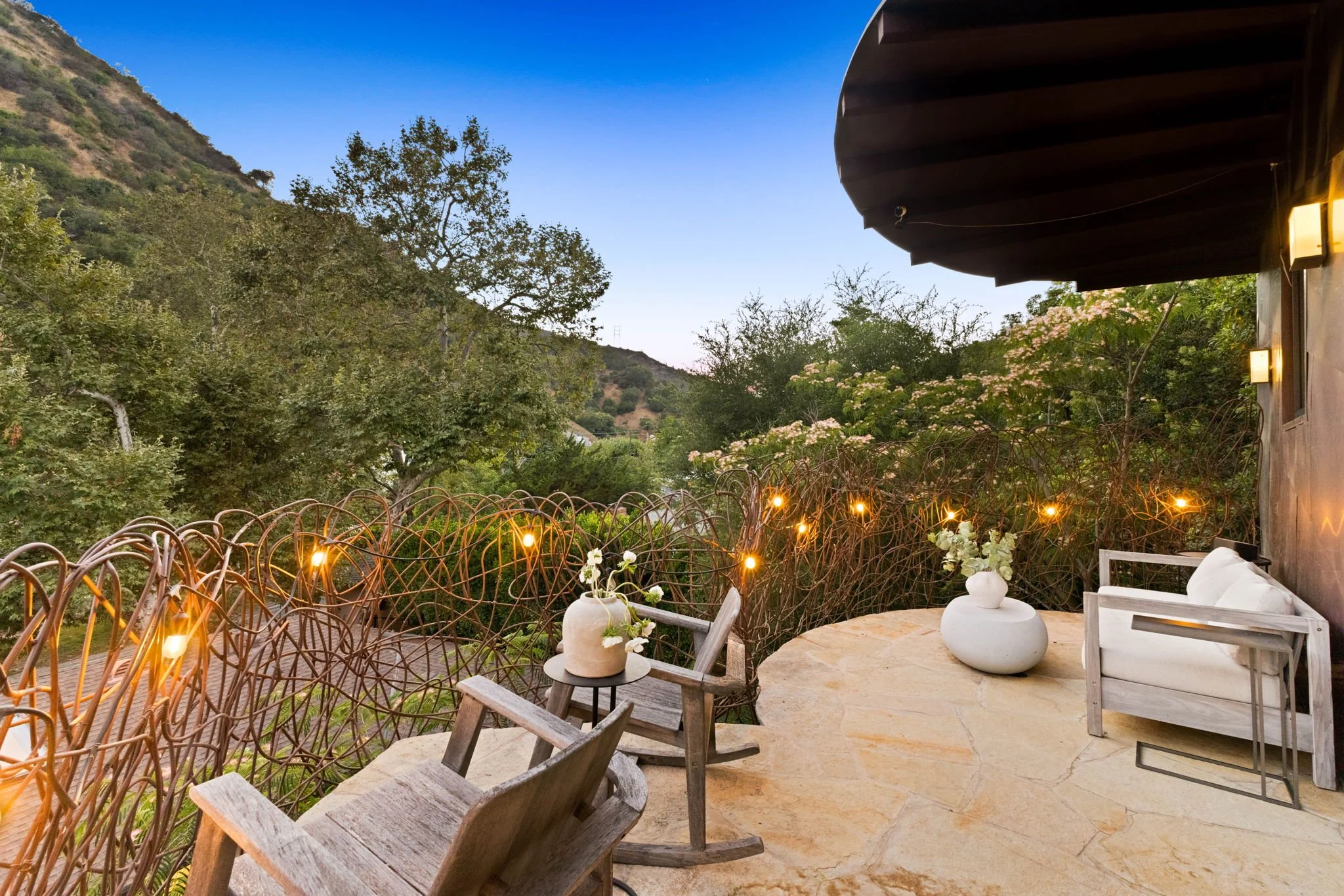 A balcony with two wooden rocking chairs overlooking canyon views in a Mandeville canyon California home.