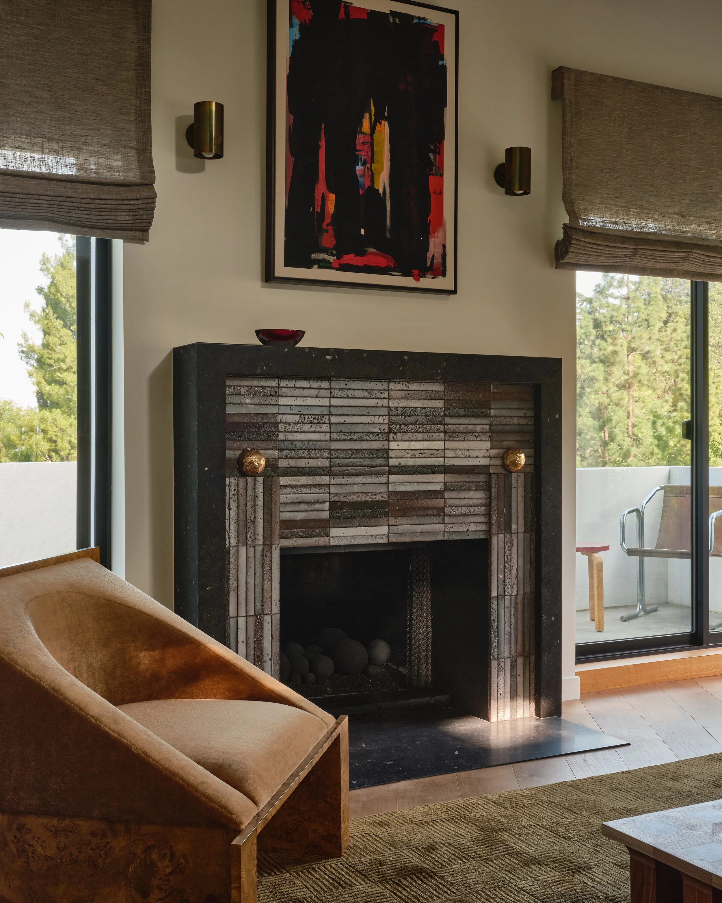 Comedian Anthony Jeselnik’s living room by Riccio Vidaurre Design – A modern tiled fireplace clad in Eco Outdoor’s Either Lava sticks tile with a honed granite mantle and bronze spheres.