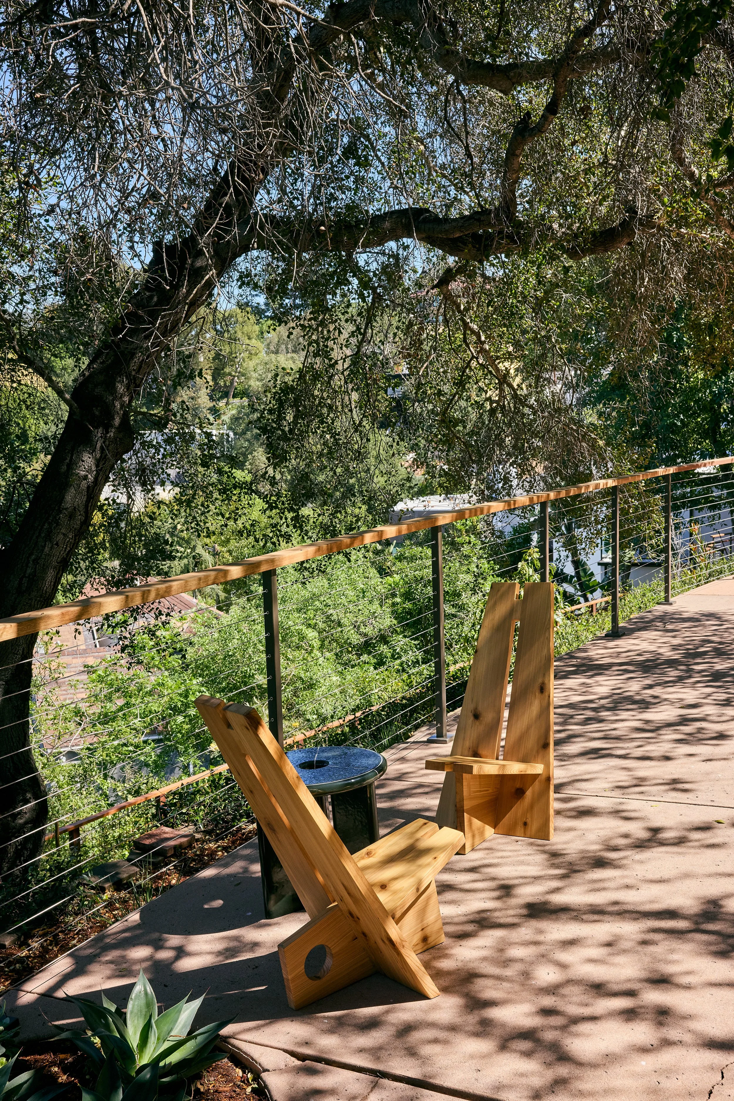 Anthony Jeselnik’s back yard, interior design by Riccio Vidaurre Design – Along the terrace, the “Caipira Campfire Chairs” by Nikolai Lafuge paired with the sculptural ceramic “Deya Side Table” by Ferm Living.