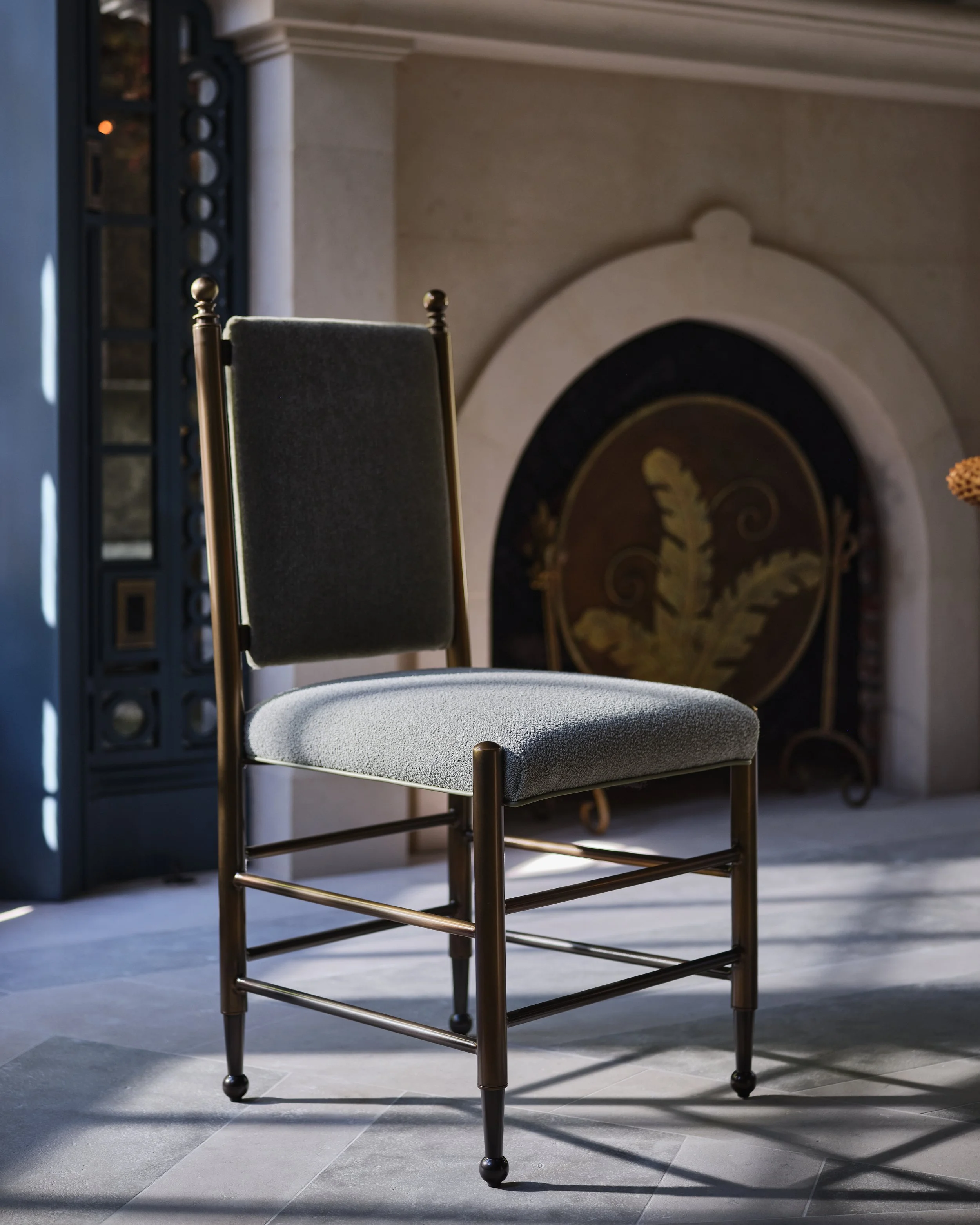 A chair with a metal frame and upholstered seat and backrest in a room with a fireplace.