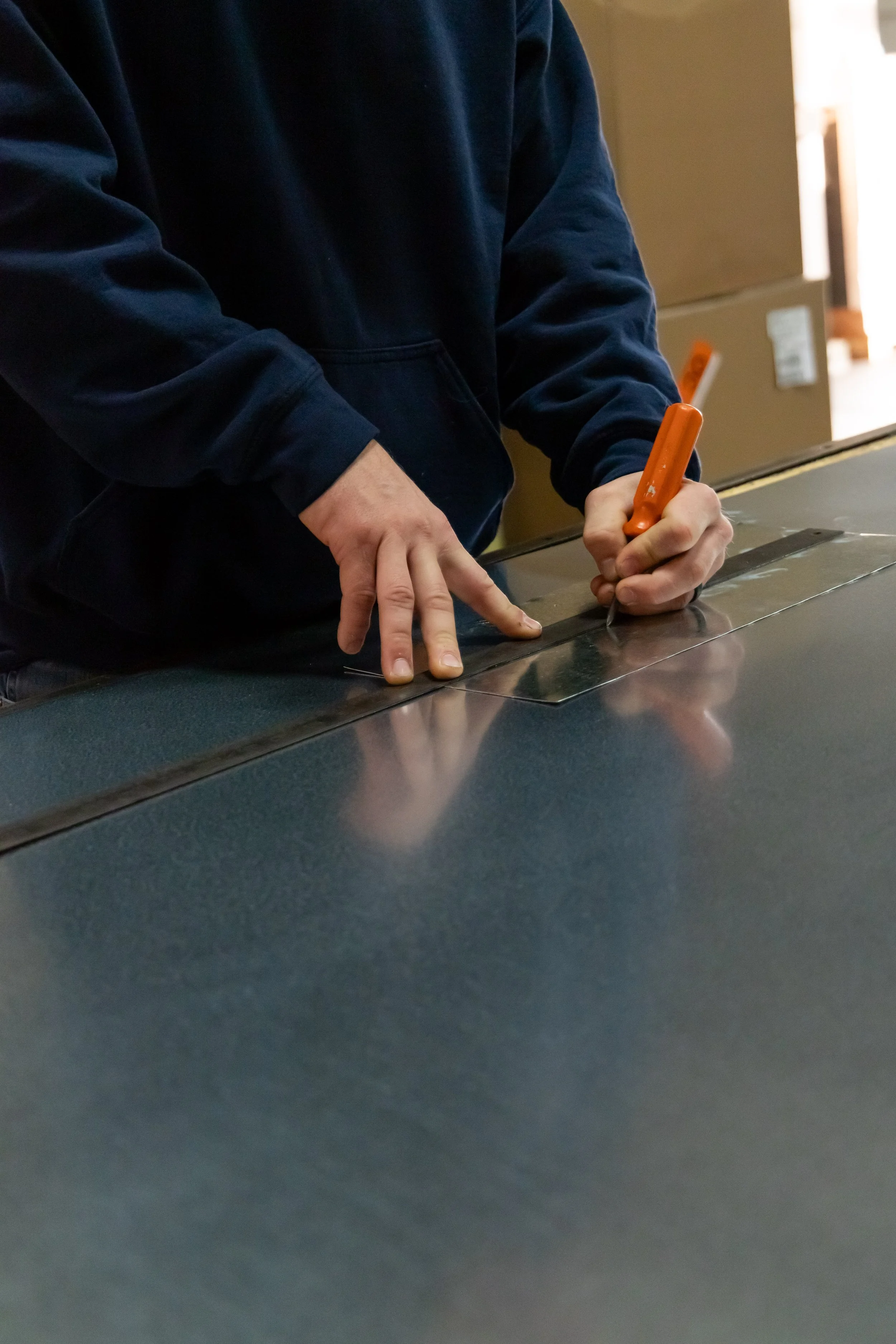 ilello using an orange marker to mark sheet metal.