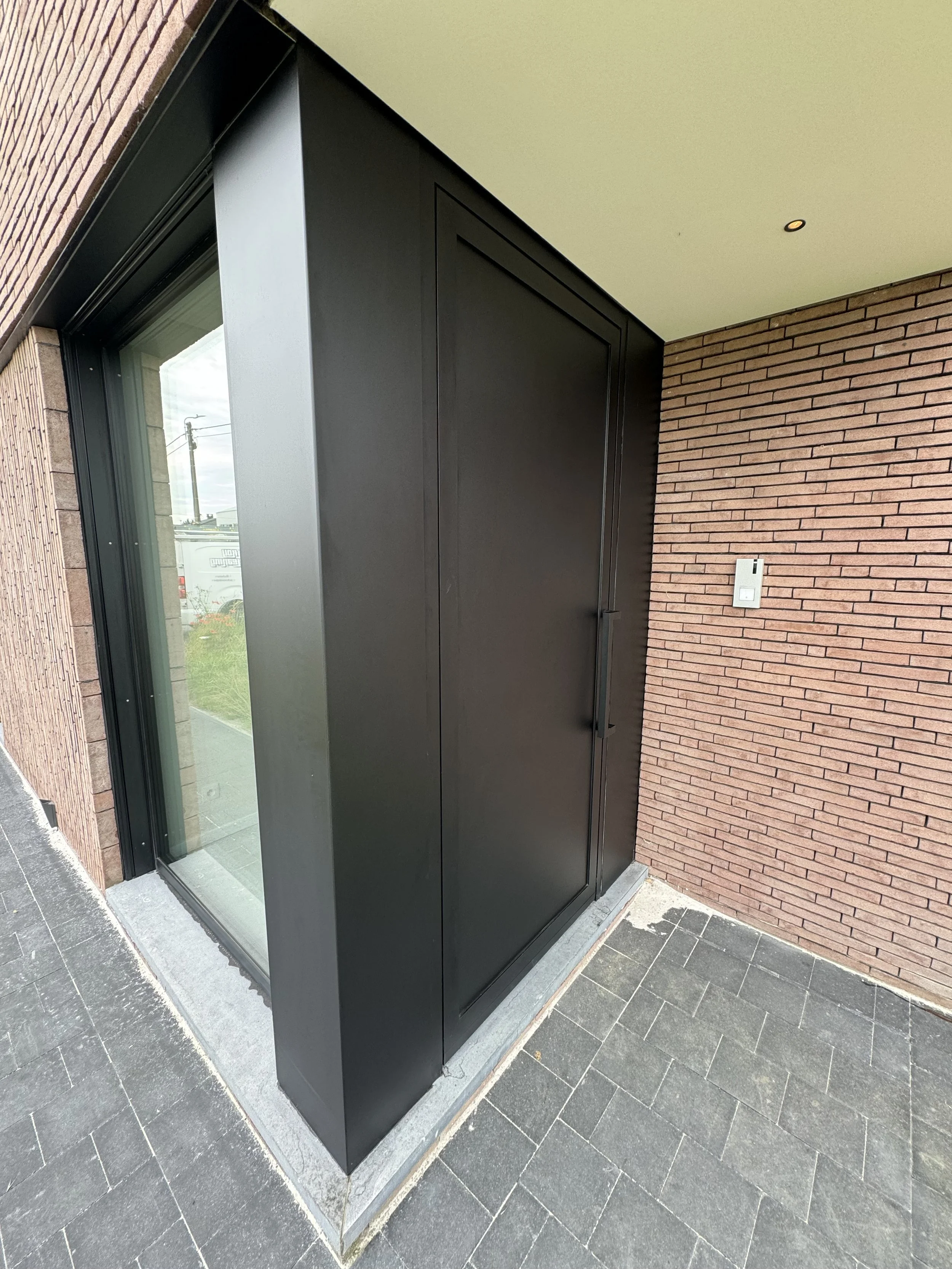 Zwart metalen deur die een dieptereiniging gehad heeft en terug proper is.