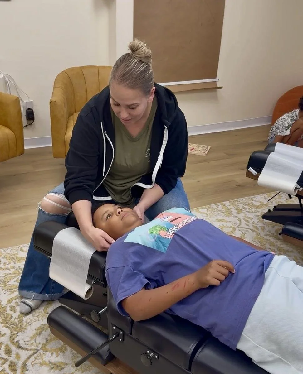 Dr. Jennifer Gordon gently supporting a boy’s head and neck while he lies on a chiropractic treatment table.
