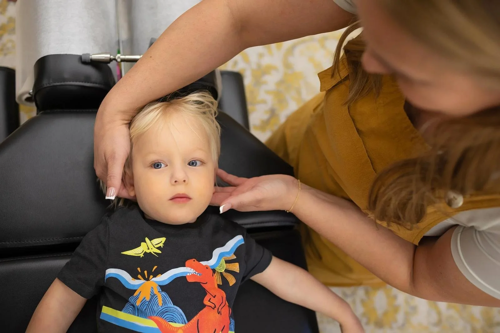 Dr. Jennifer Gordon gently supporting a young child’s head and neck during a pediatric chiropractic assessment.