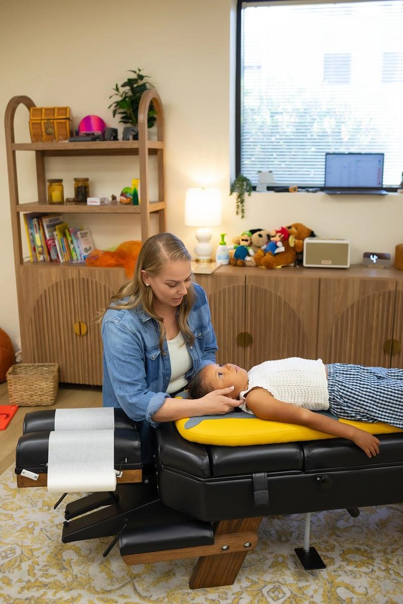 Dr. Jennifer Gordon gently supporting a child’s head and neck during a pediatric chiropractic assessment.