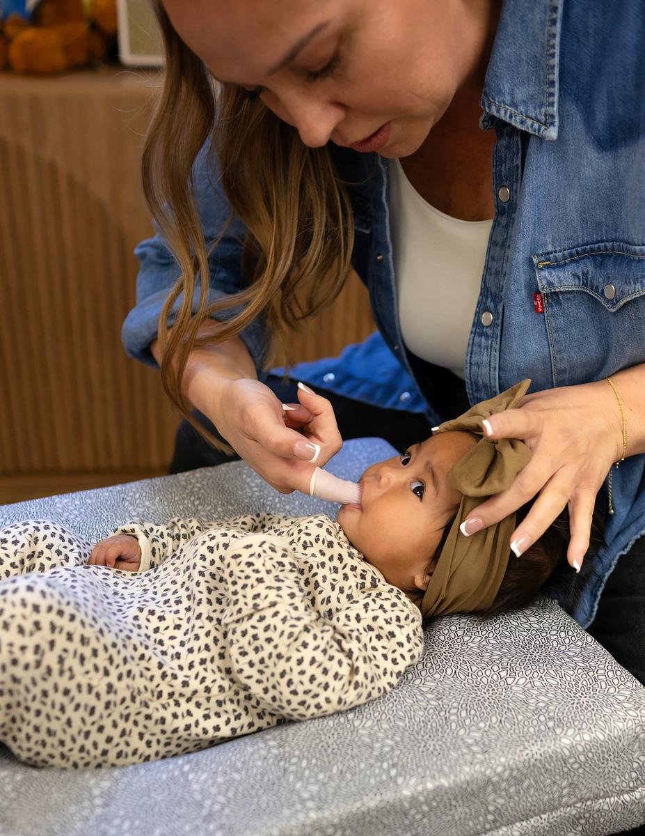 Dr. Jennifer Gordon performing a gentle oral assessment on an infant lying on a changing pad at Taproot Chiropractic.