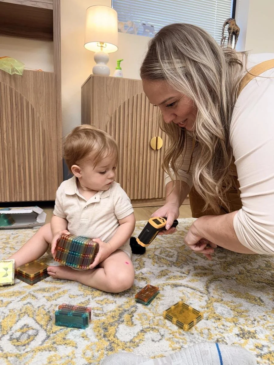 Dr. Jennifer Gordon interacting with a toddler playing with magnetic building tiles at Taproot Chiropractic.