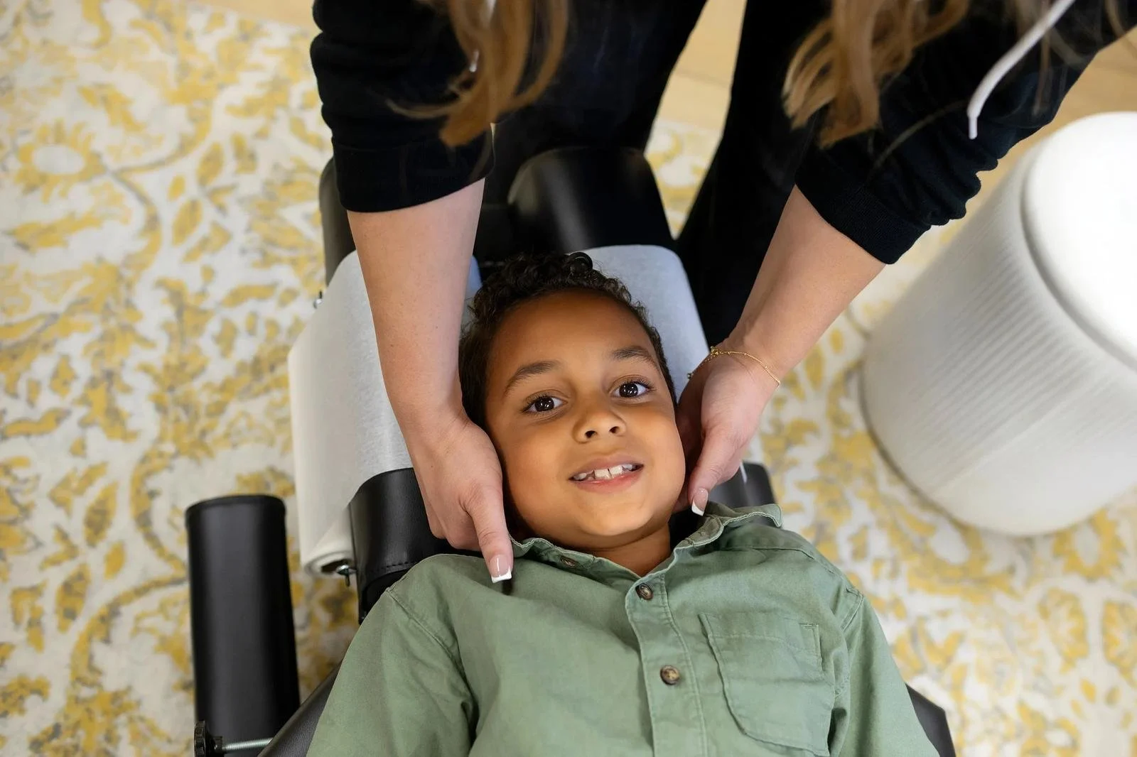 Dr. Jennifer Gordon gently supporting a young boy’s head and neck during a pediatric chiropractic assessment.
