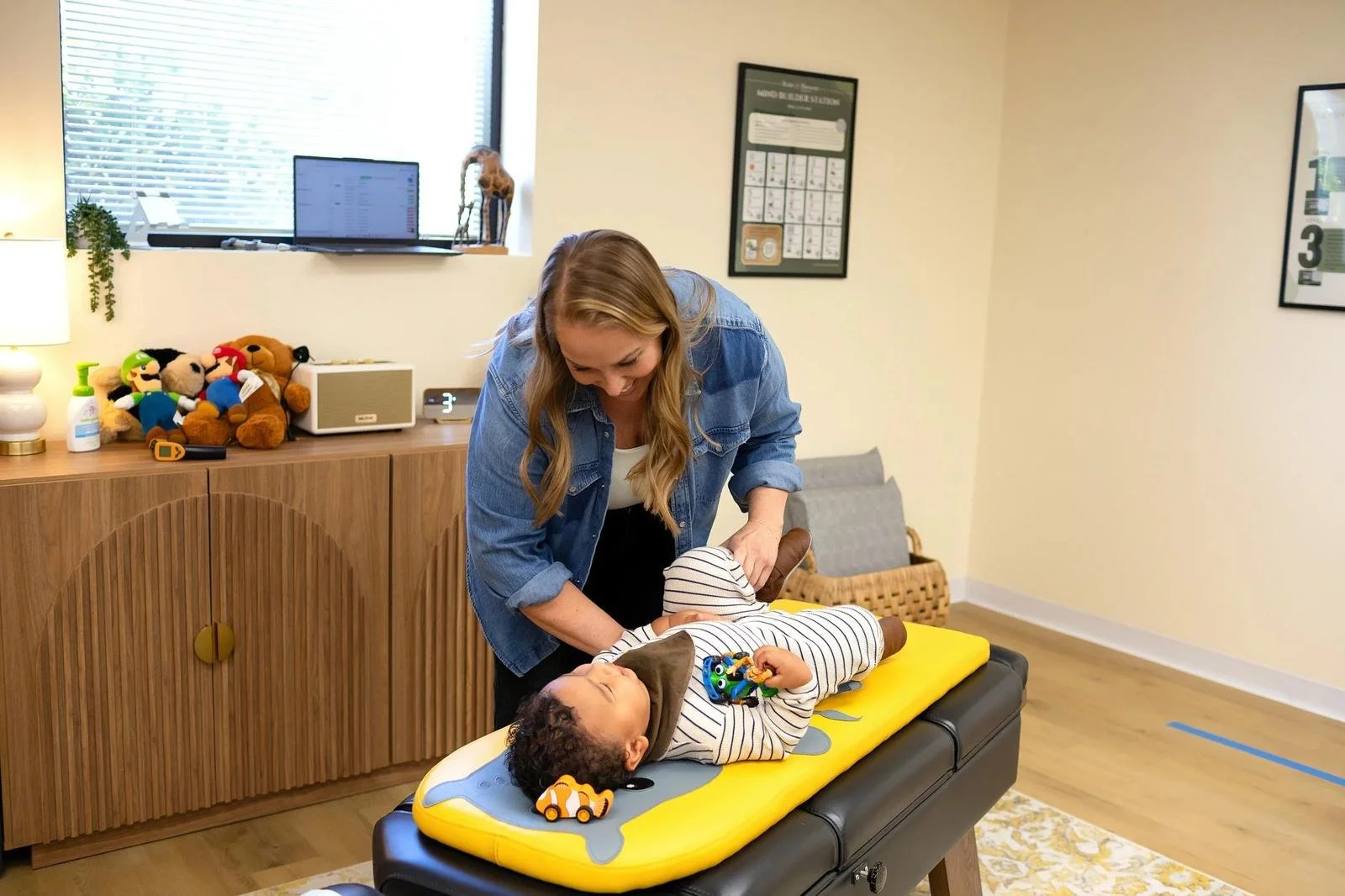 Dr. Jennifer Gordon gently checking a toddler’s leg while the child lies on a pediatric chiropractic table at Taproot Chiropractic.